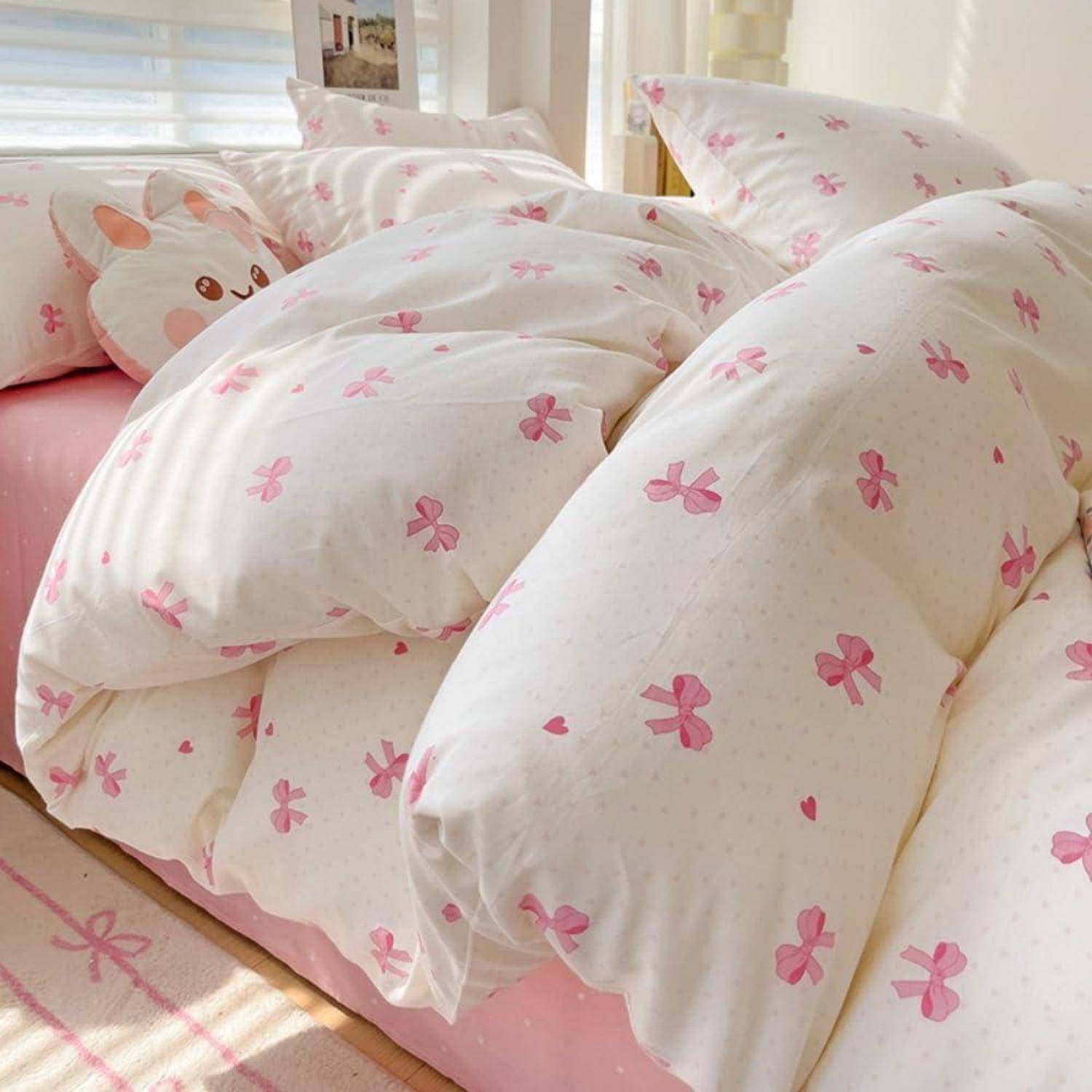 Rosa gepunktete Bettwäsche mit Mustern mit Kissen und Bettdecke auf einem ordentlich gemachten Bett in einem hellen Schlafzimmer.
