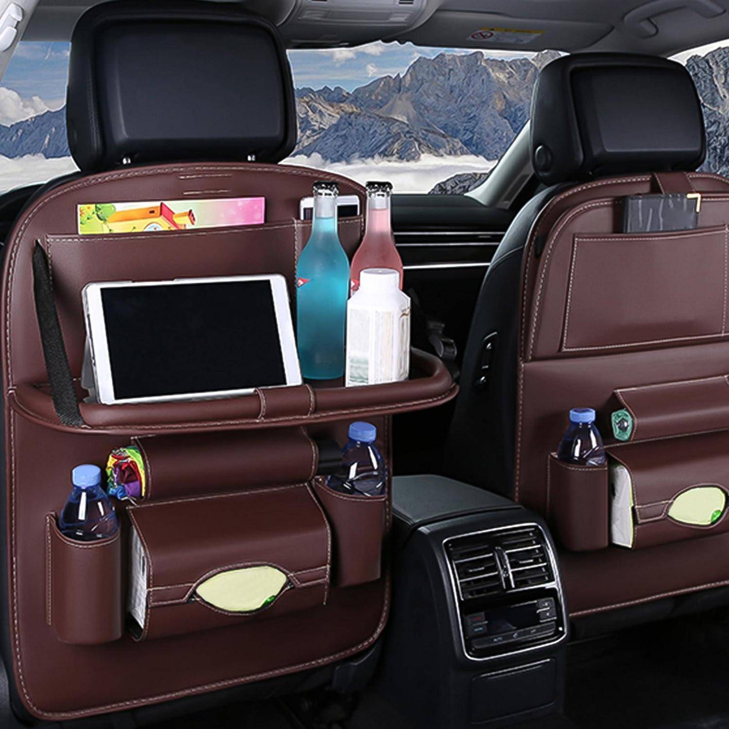 Autositz-Organizer auf beiden vorderen Rückenlehnen, mit einem Tablet, Flaschen, Tüchern und kleinen Gegenständen in einem Auto mit Bergaussicht außerhalb.