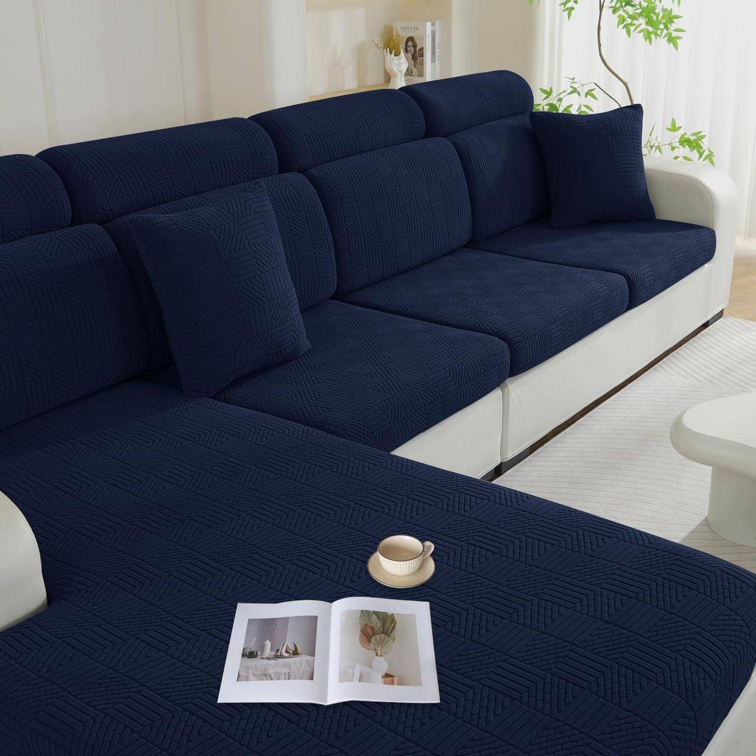 Marineblau farbiges Ecksofa mit passenden Kissen in einem hellen Wohnzimmer, mit einer offenen Zeitschrift und einer Tasse auf dem Ottomane.