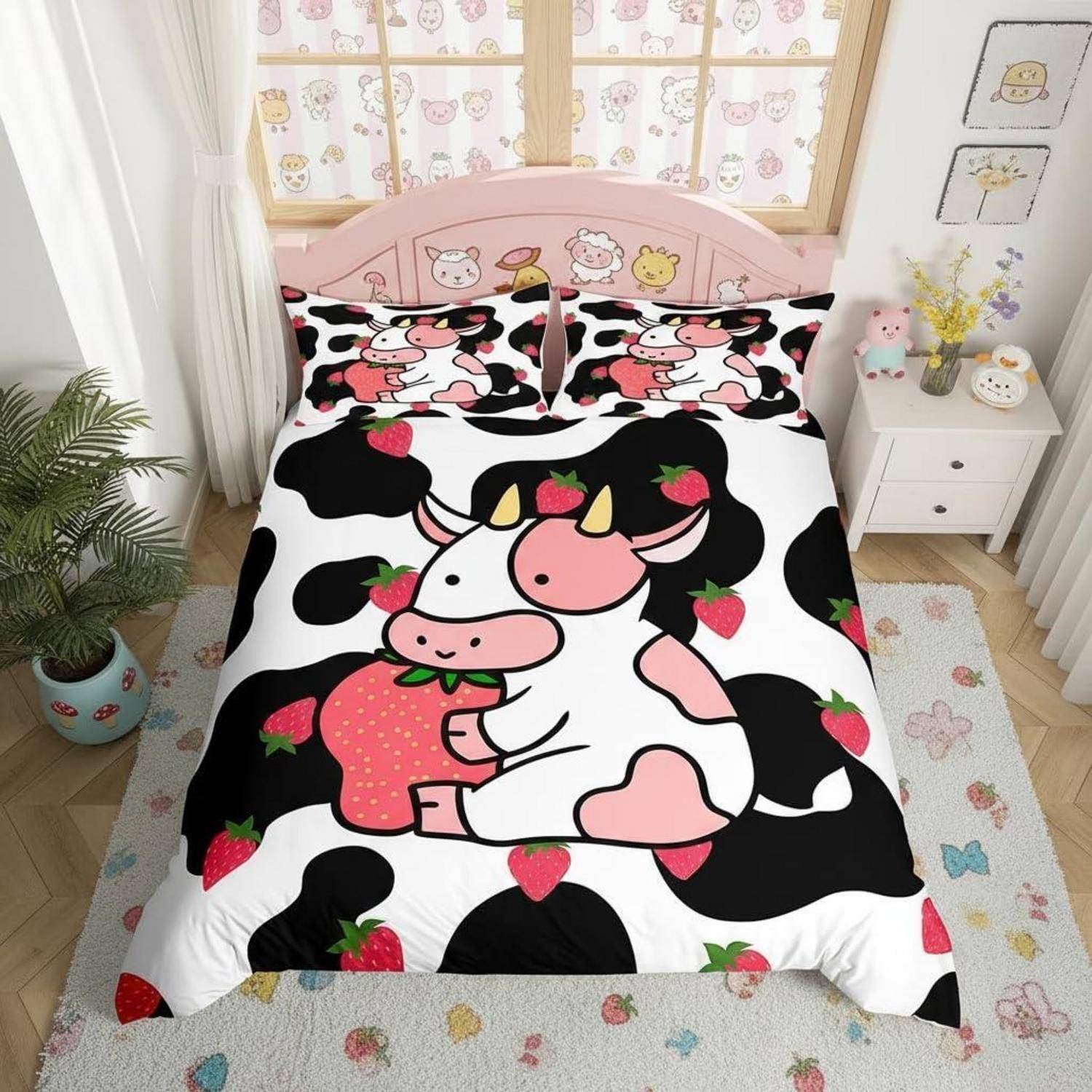 Rosa kuhthematisches Bett mit passenden Kissenbezügen, schwarzweiße Erdbeer-Kuh-Bettdecke, in einem pastellfarbenen Kinderzimmer mit Nachttisch und Dekoration.