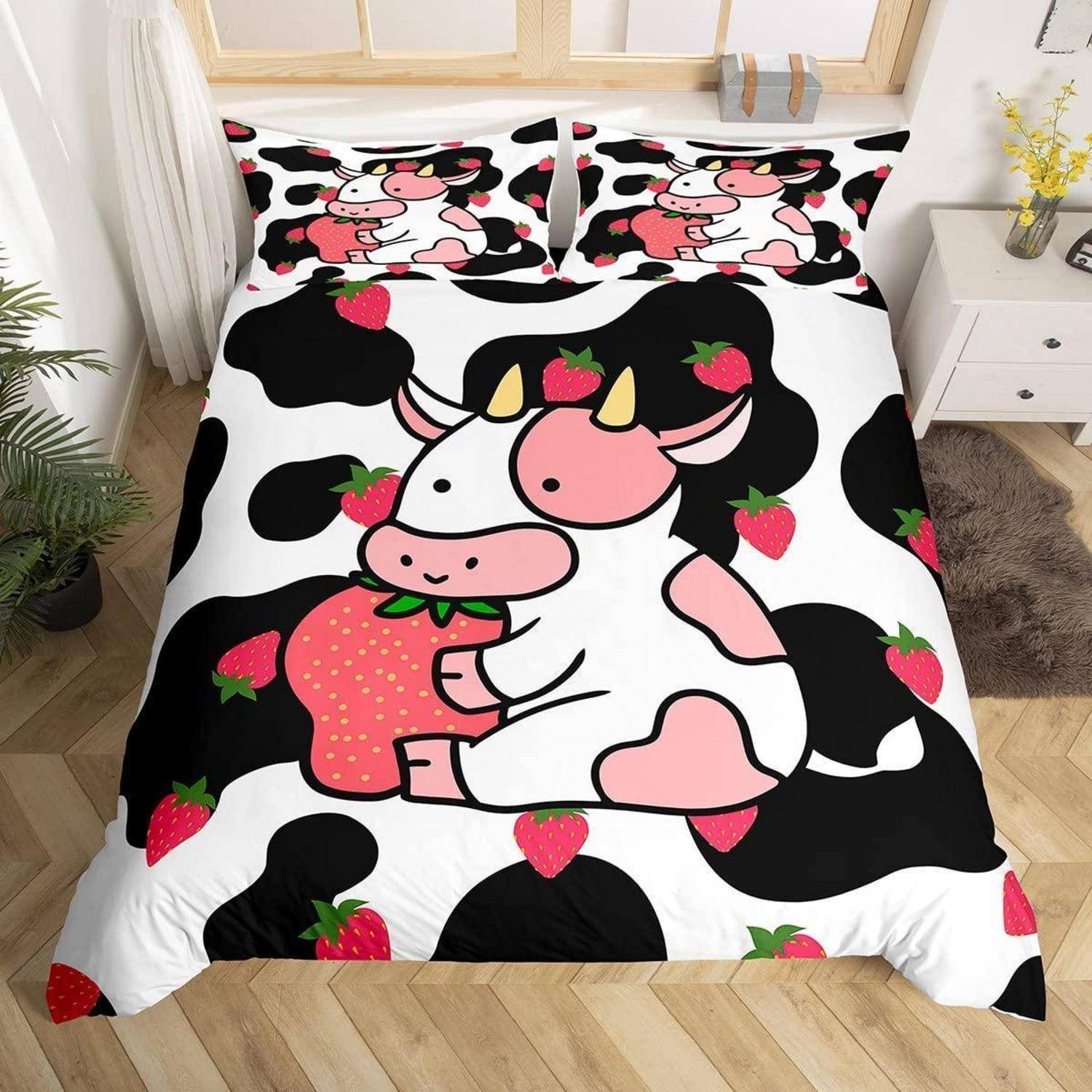 Ein Bett mit einer schwarz-weißen Kuhflecken-Steppdecke und Kissen mit einer niedlichen Cartoon-Kuh, die eine Erdbeere hält, in einem hellen Schlafzimmer.