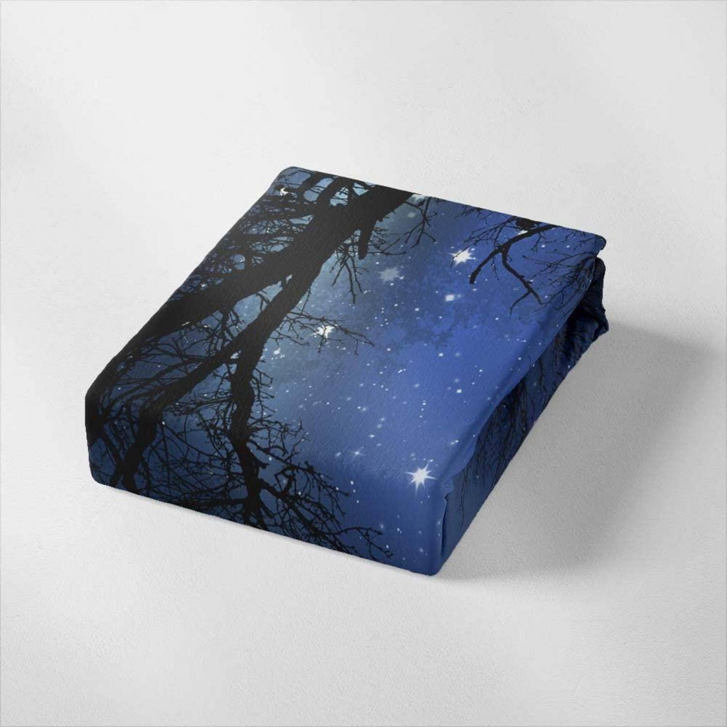 Quadratisches Stoffkissen mit einem blauen Nachthimmel- und Baumastmuster auf hellgrauem Untergrund.