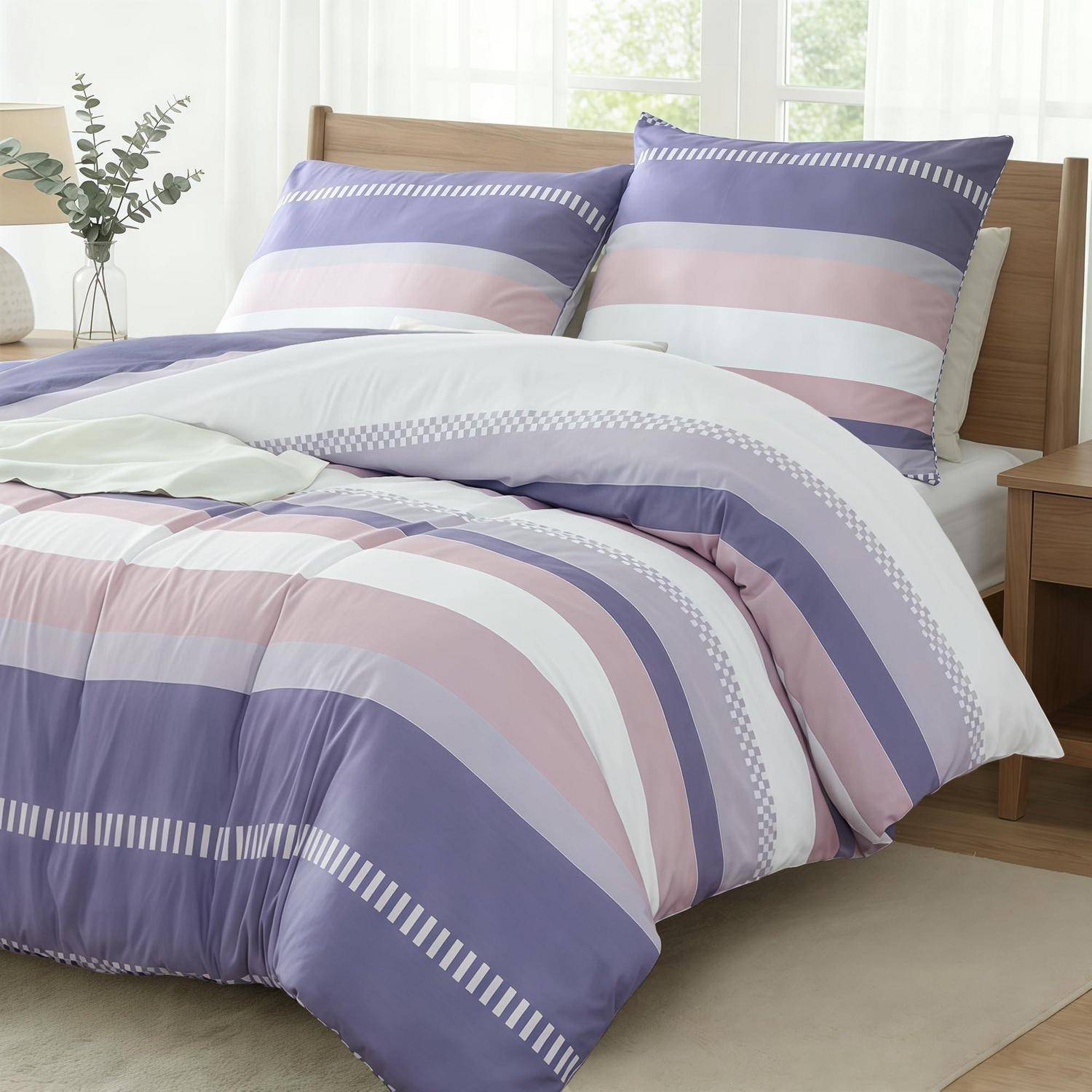 Bett mit Bettwäsche in Lavendelblau, Rosa und Weiß gestreift und passenden Kissen in einem hellen Schlafzimmer.