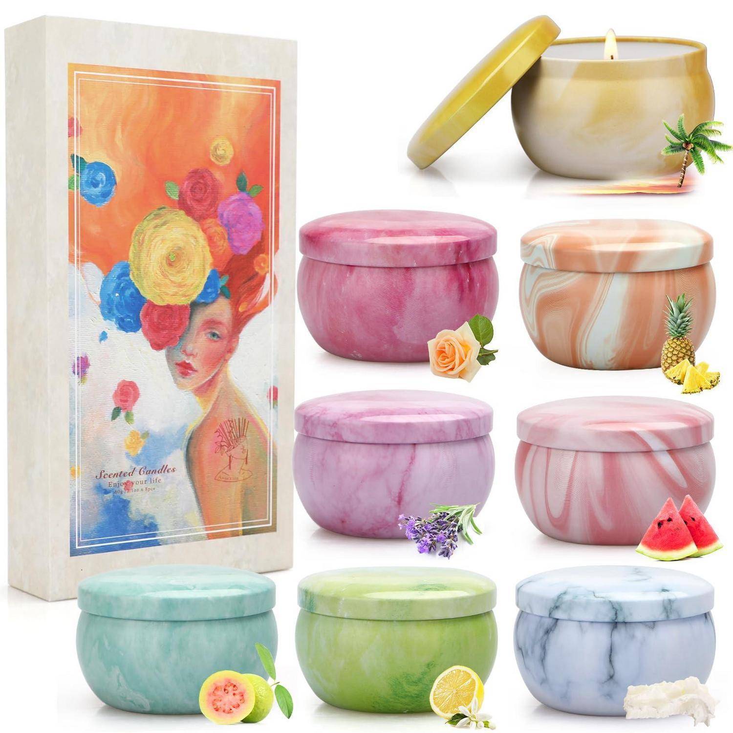 Verschiedene duftende Kerzen in runden dekorativen Gläsern mit pastellfarbenen Marmormuster, gezeigt neben einer Blumen-Geschenkbox.