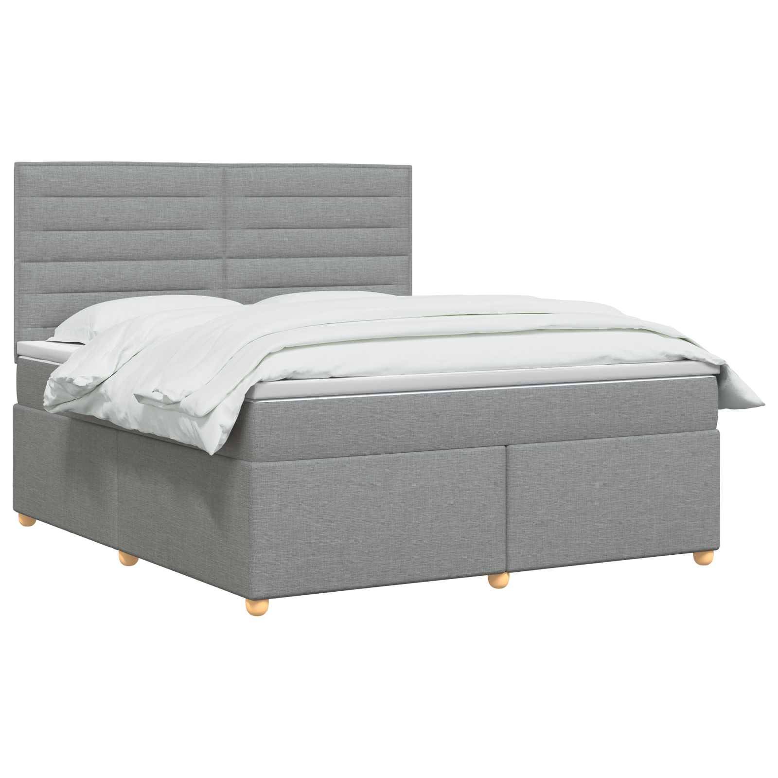 Grau gepolstertes Bett mit hohem gepolstertem Kopfteil, weißer Bettwäsche und einem Sockel im Lagerstil auf weißem Hintergrund.