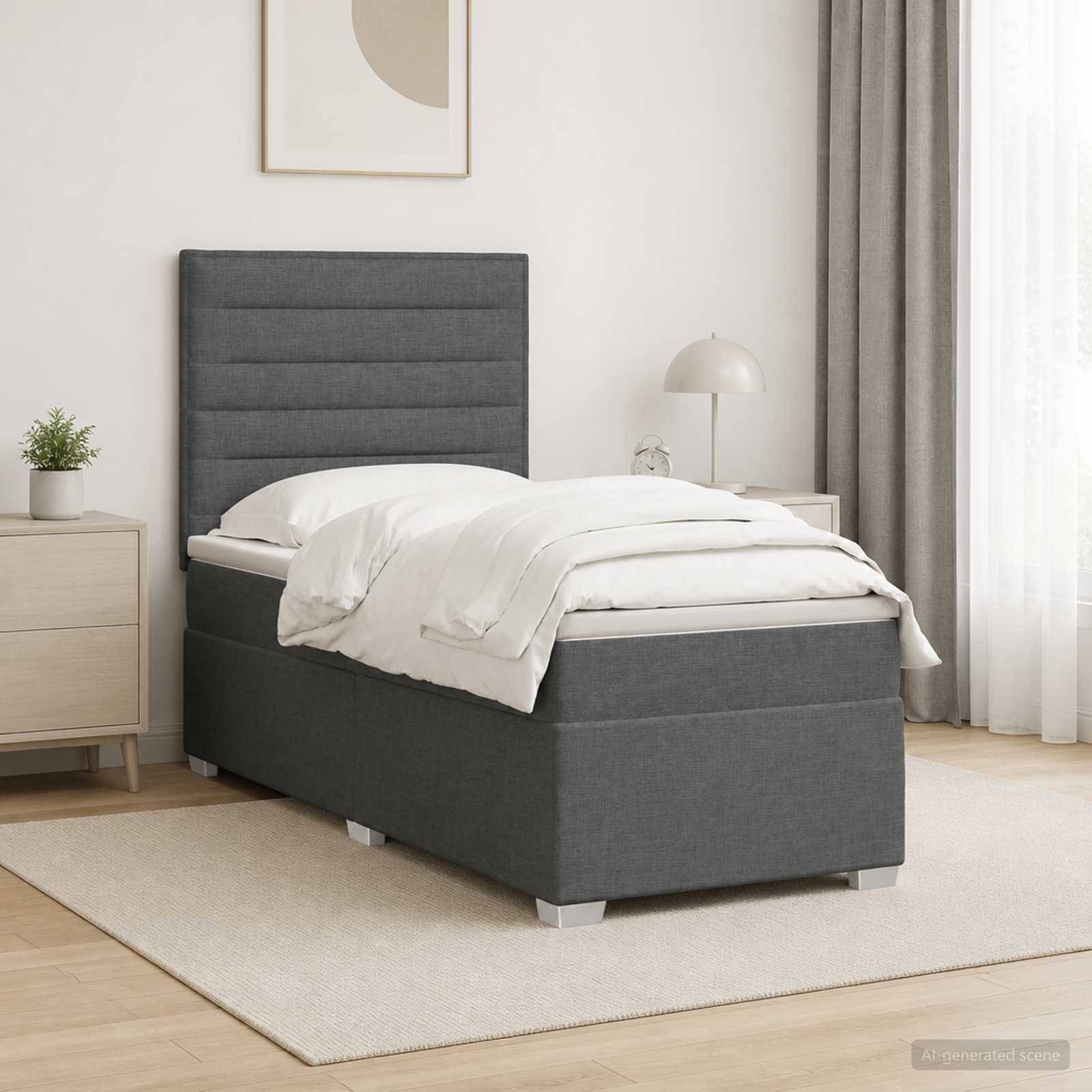 Modernes Schlafzimmer mit einem grau gepolsterten Einzelbett, weißer Bettwäsche, Nachttischen, Lampe, Pflanze und neutraler Dekoration auf einem hellen Teppich.