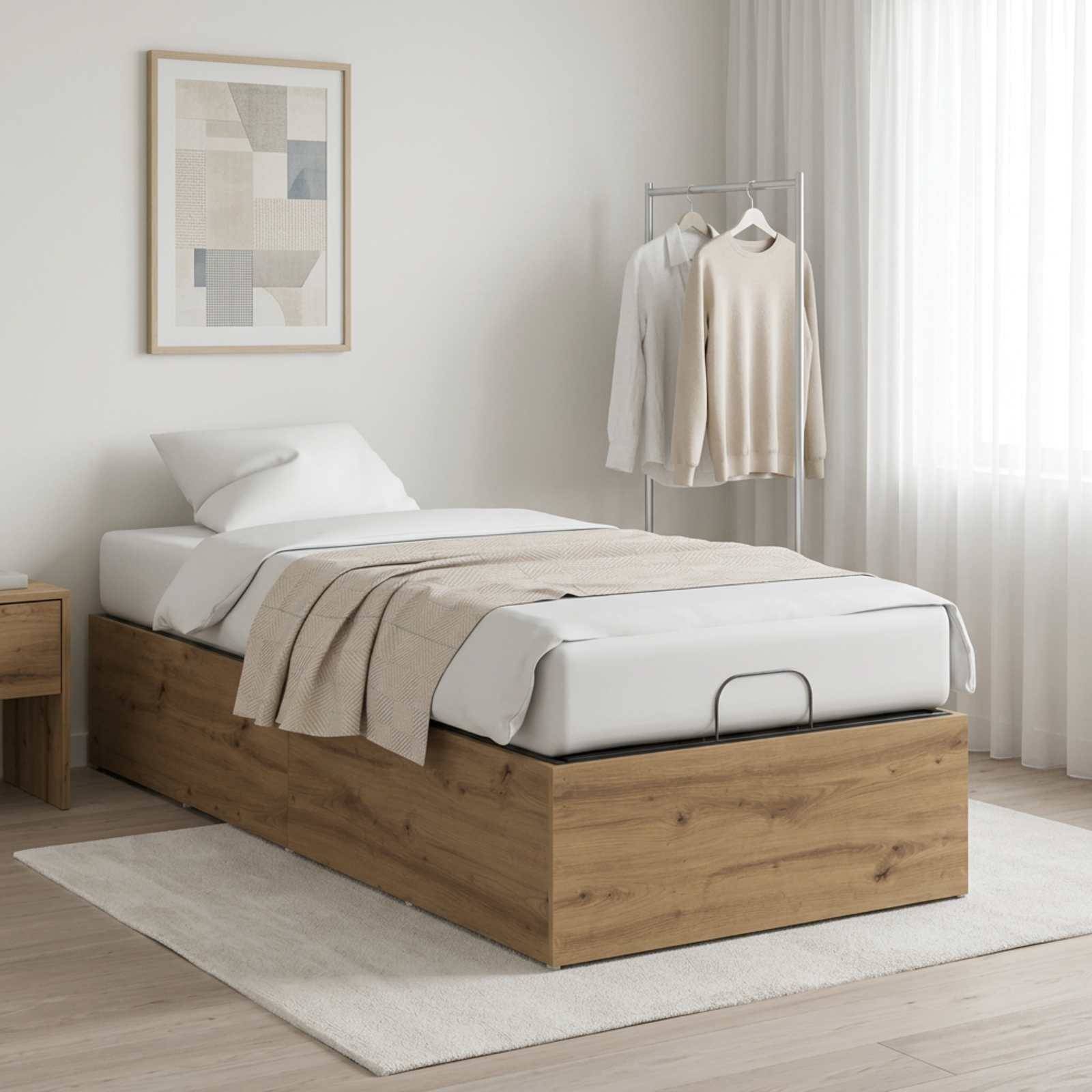 Minimalistisches Schlafzimmer mit einem Einzelbett auf einer Holzlagerbasis, beigefarbiger Decke, gerahmter Wandkunst, Kleiderstange und transparenten Vorhängen.