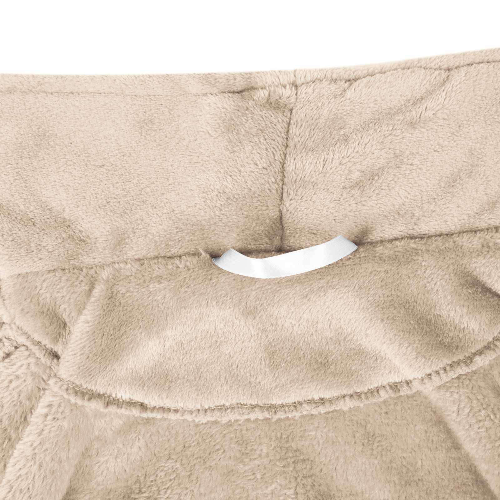 Nahaufnahme von beiger Plüschpolsterung mit einer gesteppten Naht und einer kleinen weißen Stoff-Schlaufe oder Lasche in der Nähe der Mitte.