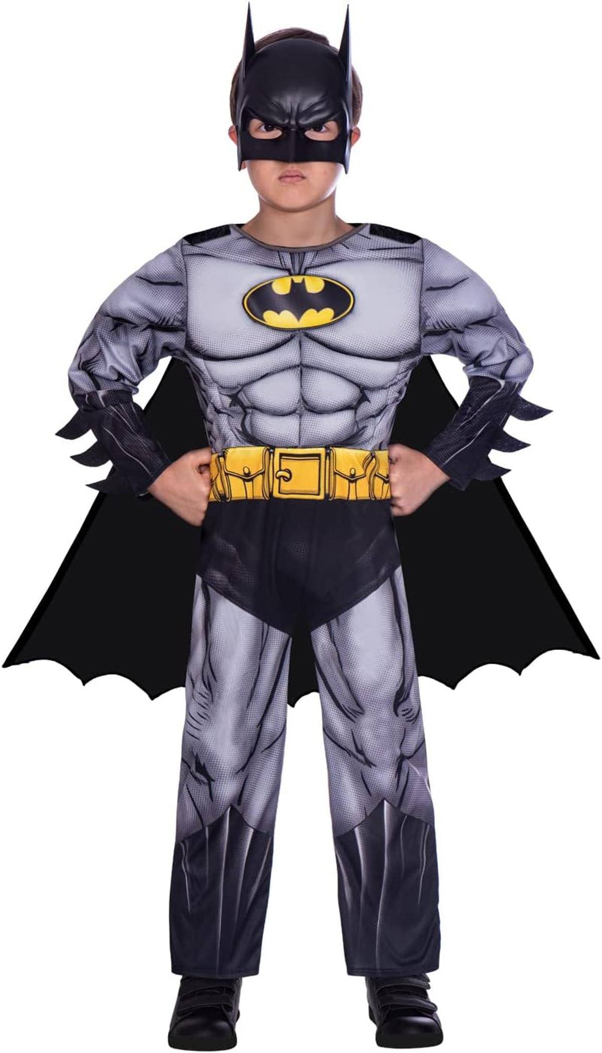 Kind in einem Batman-Kostüm gekleidet, frontal stehend mit den Händen auf den Hüften vor weißem Hintergrund.