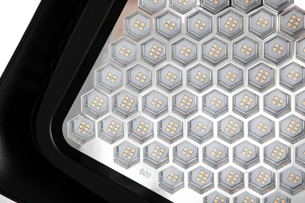 Nahaufnahme eines sechseckigen LED-Lichtpanels, das ein wabenförmiges Gitter aus kleinen Glühbirnen hinter einem schwarzen Rahmen zeigt.