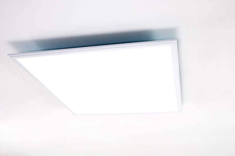 Ein quadratisches weißes LED-Deckenlichtpanel, das bündig an einer weißen Decke montiert ist.