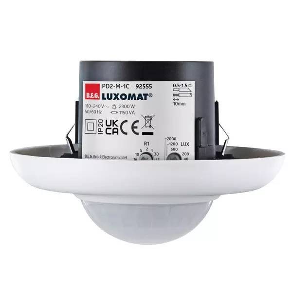 Ein weiß montierter Deckenmelder mit schwarzem Steuermodul mit der Bezeichnung „LUXOMAT