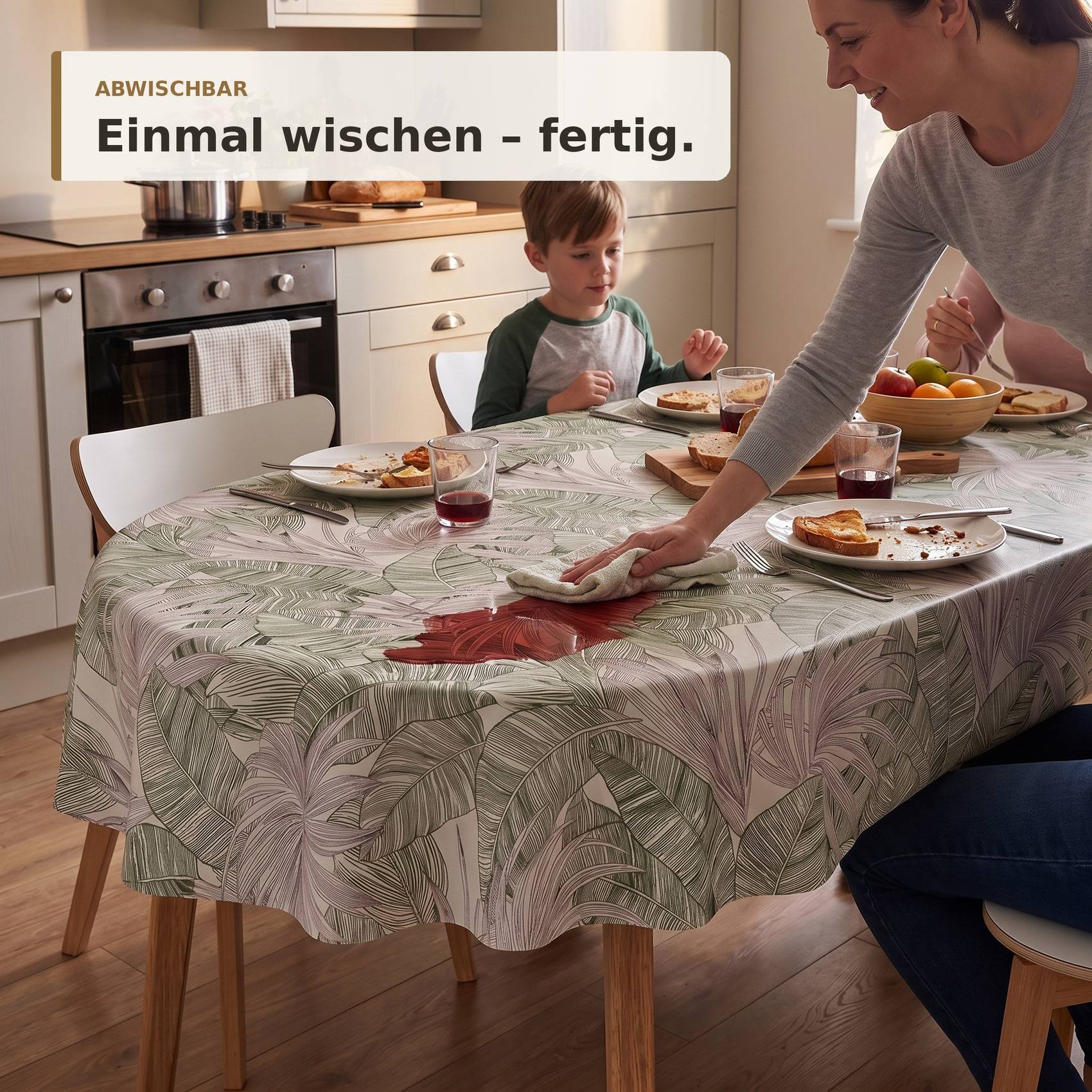 Frau wischt einen gemusterten Esstisch in einer Küche ab, während ein Kind in der Nähe sitzt; der Text lautet „ABWISCHBAR" und „Einmal wischen - fertig."