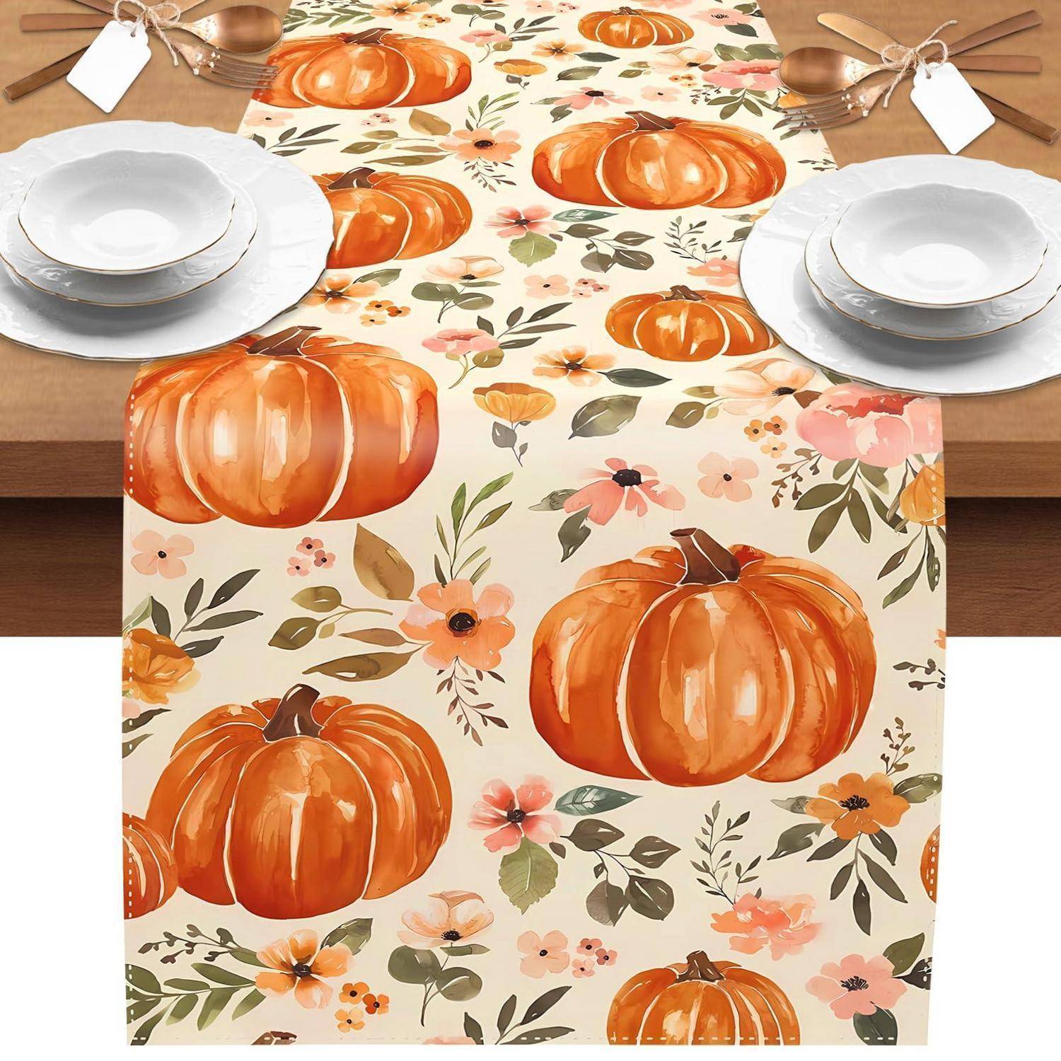 Kürbis- und Blumenlaufer auf einem Esstisch mit weißen Tellern und Besteck für ein herbstliches Essen eingedeckt.