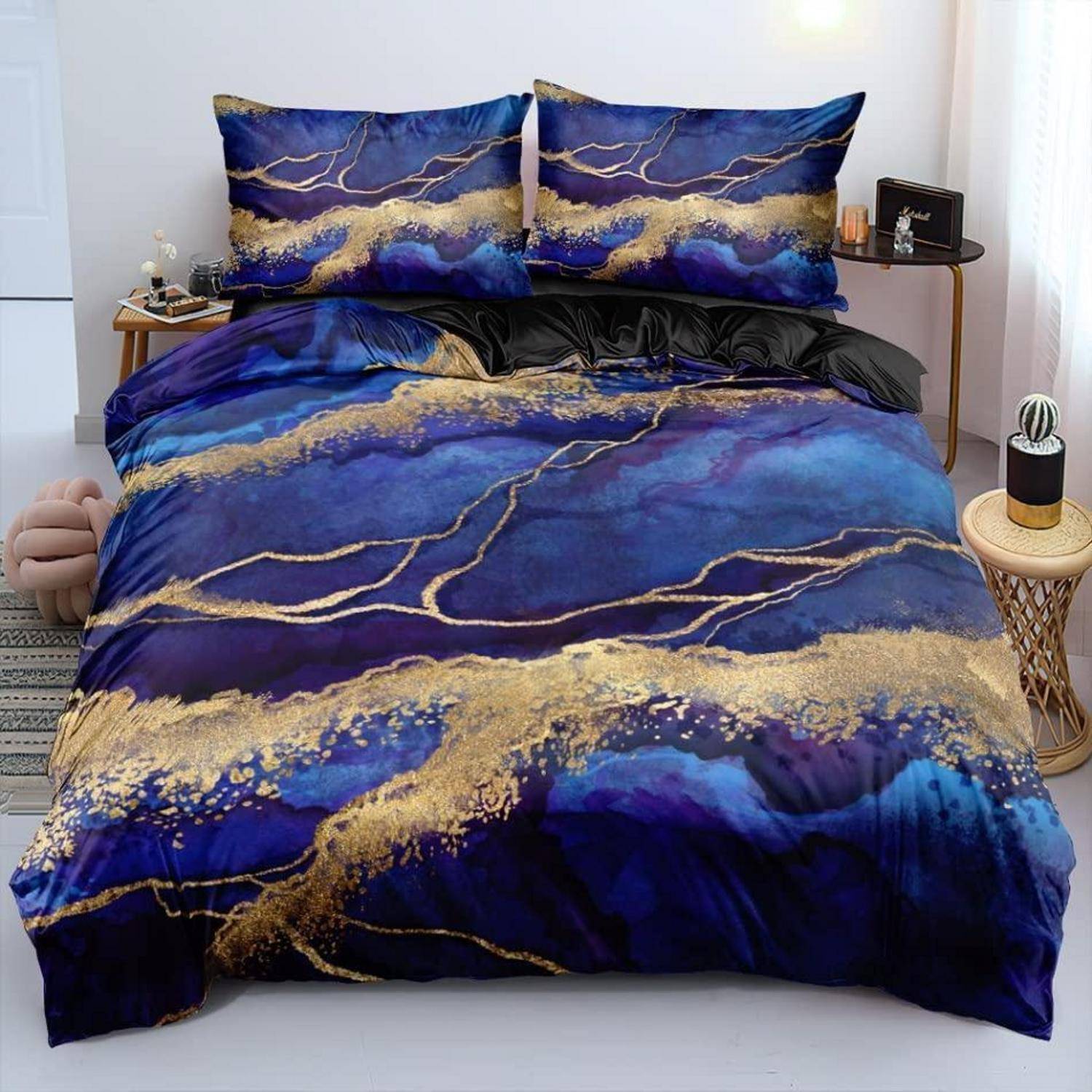 Ein Bett mit blau-goldener, abstrakt gemusterter Bettwäsche und passenden Kissen in einem hellen Schlafzimmer.
