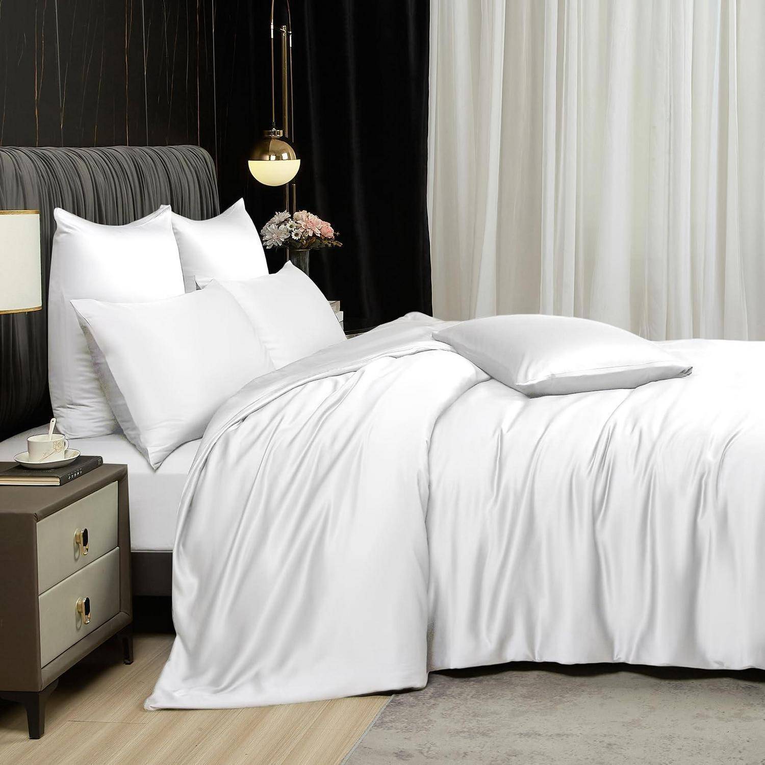 Ein ordentlich gemachtes Bett mit weißer Bettwäsche und Kissen neben einem Nachttisch in einem modernen, sanft beleuchteten Schlafzimmer.
