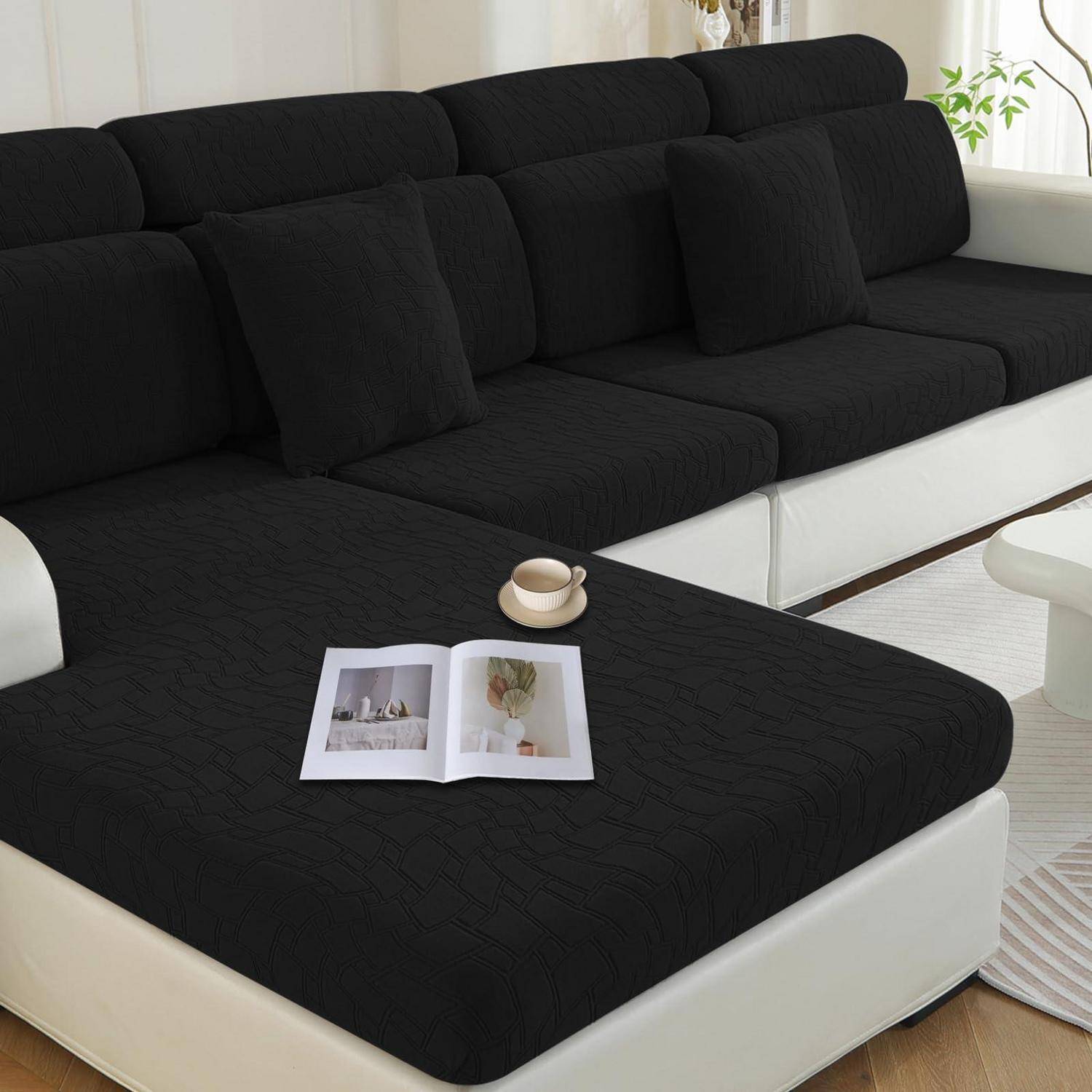Schwarzes und weißes Ecksofa in einem hellen Wohnzimmer, mit einer offenen Zeitschrift und einer Tasse auf der Chaiselongue.