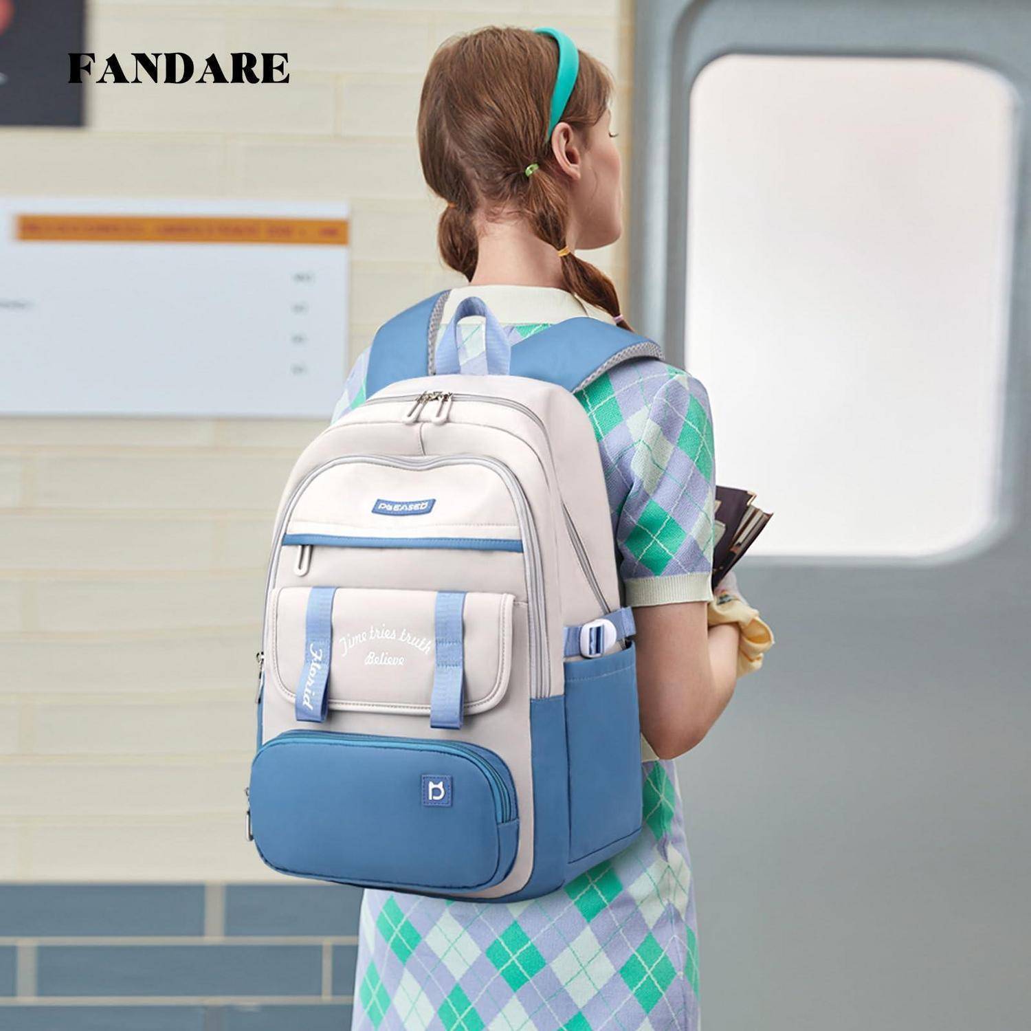 Mädchen mit einem hellblauen und beigen Rucksack, das in einem Schulflur steht, von hinten gesehen, mit dem sichtbaren Markennamen 