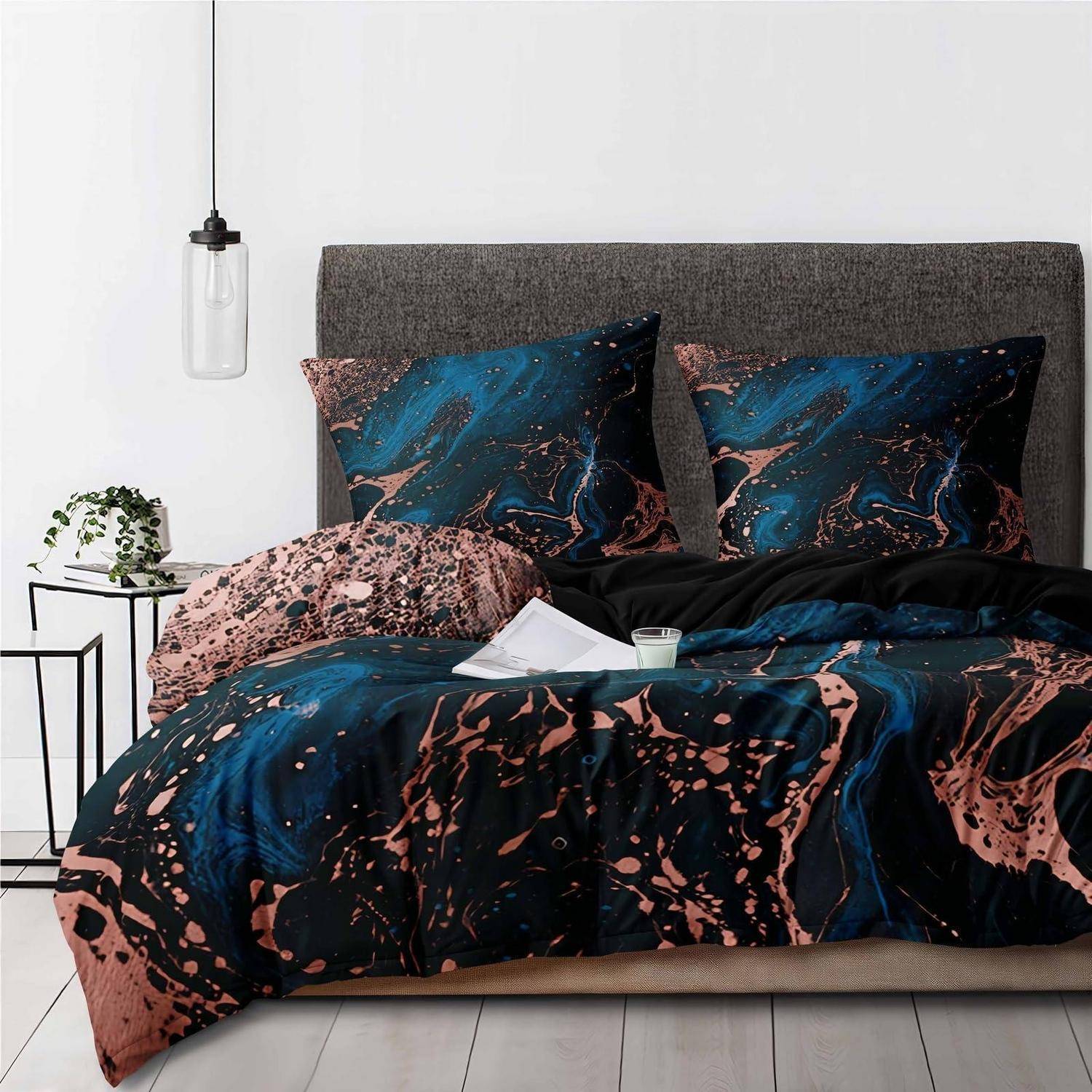 Bett mit dunkelblauem und rosa abstraktem Bettzeug und Kissen, grauem gepolstertem Kopfteil, daneben eine kleine Pflanze und eine hängende Pendelleuchte.