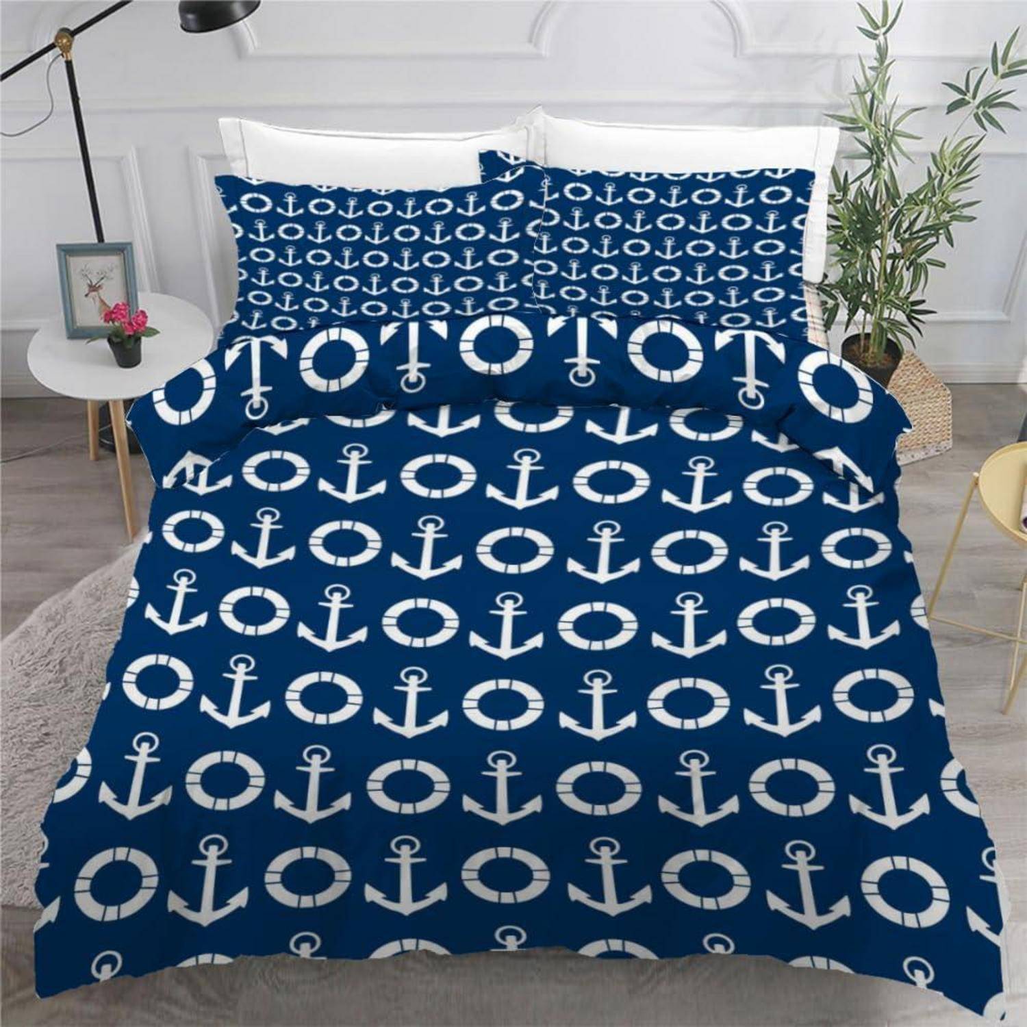 Blaue Bettwäscheset mit weißen Ankern und Rettungsringen auf einem gemachten Bett in einem hellen Schlafzimmer.
