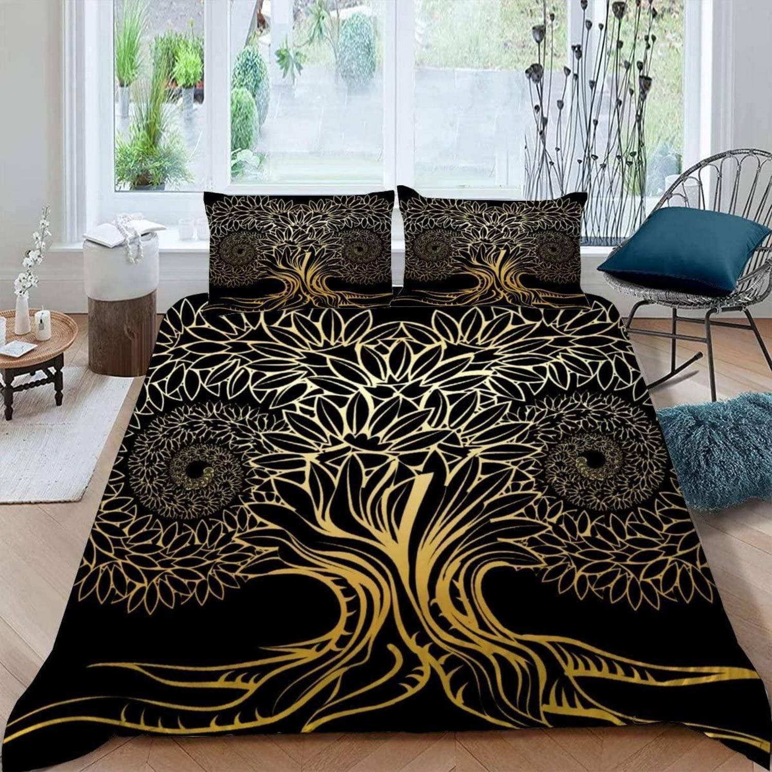 Schwarze und goldene Bettwäsche mit einem großen Baum-des-Lebens-Design auf einem Bett in einem hellen, modernen Schlafzimmer mit Stühlen und Pflanzen.