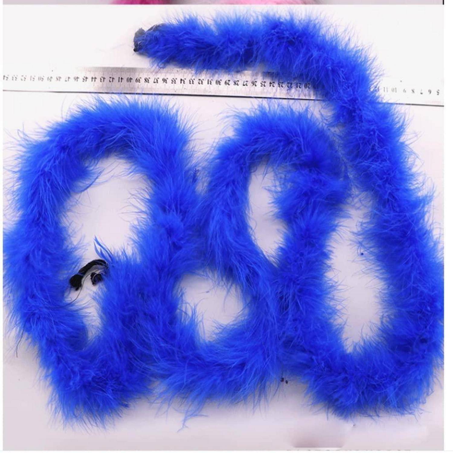 Drei blaue flauschige Pfeifenreiniger-Schleifen auf einer weißen Oberfläche unter einem Lineal angeordnet, die ihre Größe zeigen.