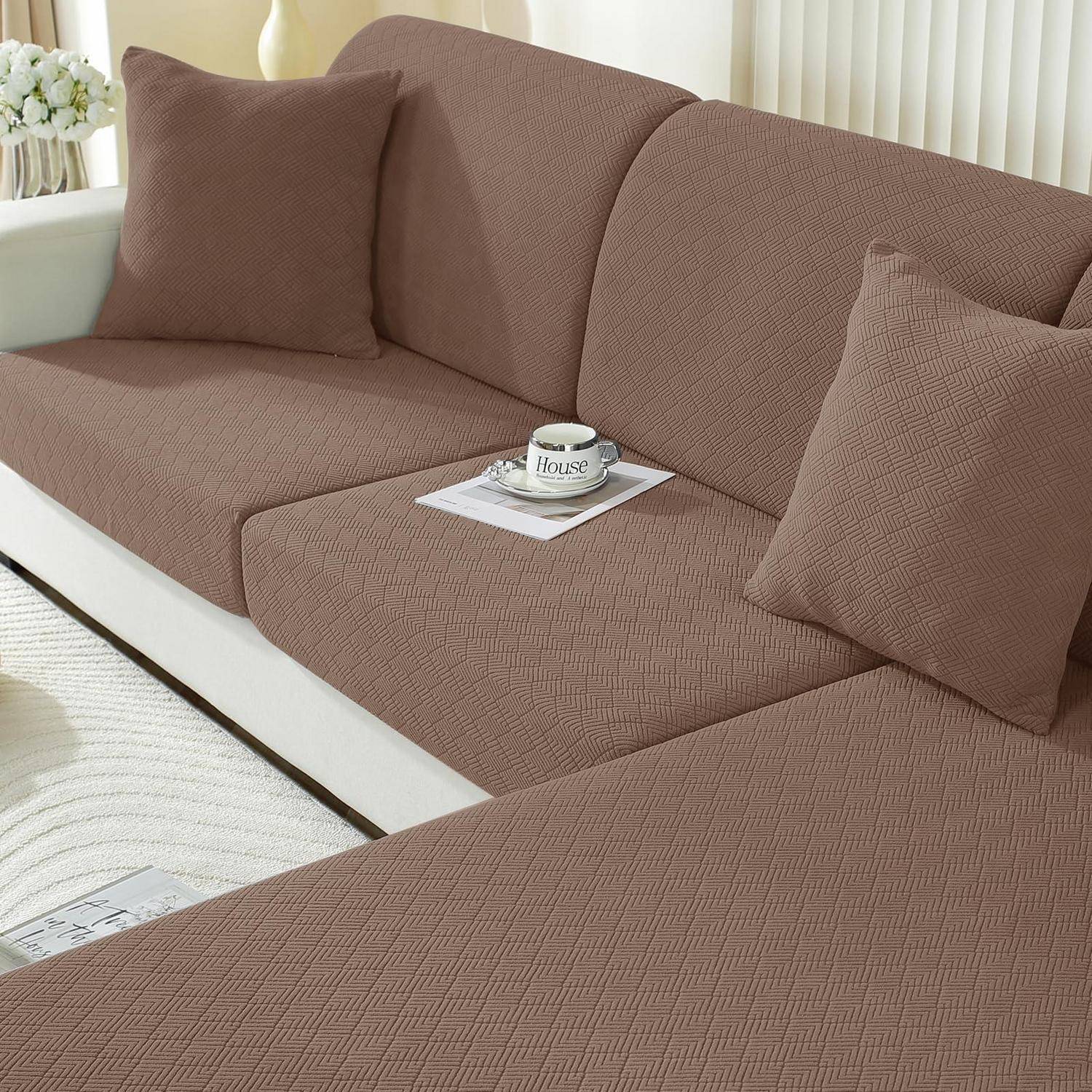 Braunes strukturiertes Sofa mit passenden Kissen und einer Zeitschrift, mit einer „House