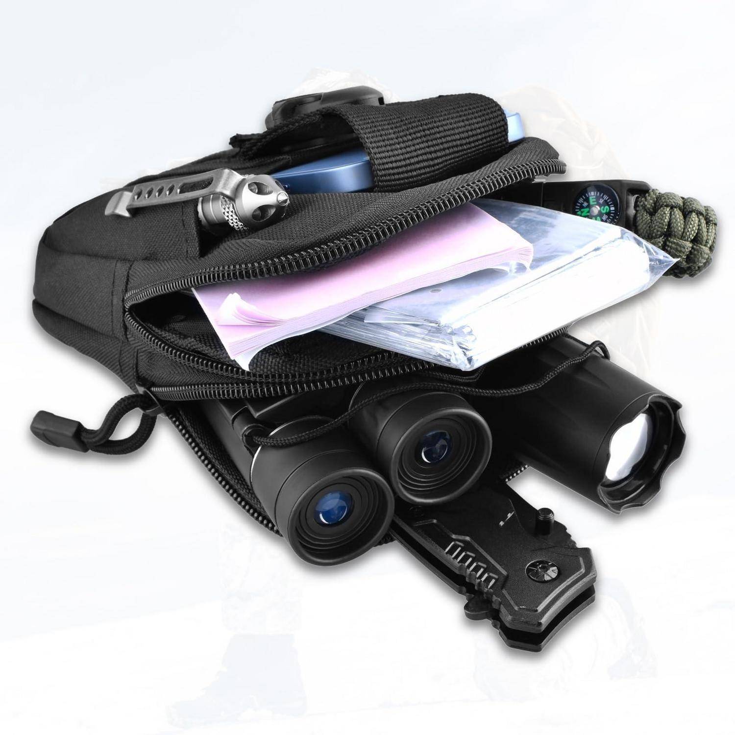 Offene schwarze Tasche gefüllt mit Überlebensmaterial, einschließlich Fernglas, Taschenlampe, Messer, Kompass, Taschenlampe und gefaltete Papiere.