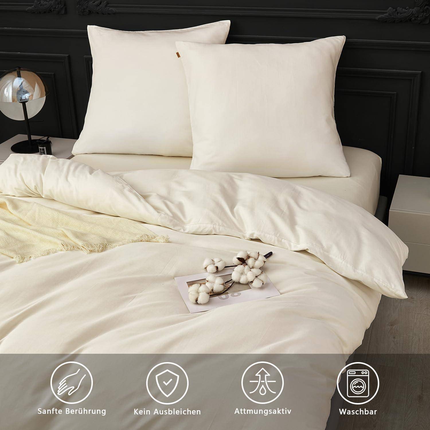 Bett mit cremefarbenem Bettdecke und Kissen in einem schwarzen Schlafzimmer; untere Symbole auf Deutsch werben für weiche Haptik, Farbbeständigkeit, Atmungsaktivität, waschbar.
