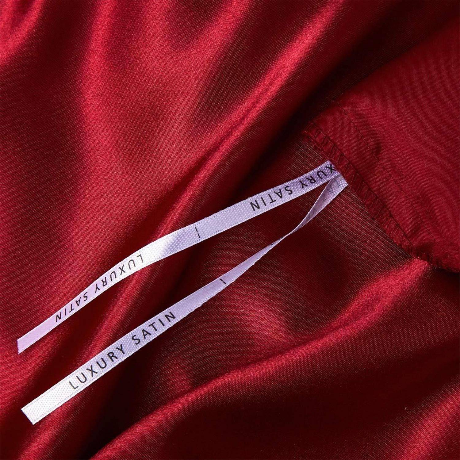 Nahaufnahme von rotem Satinstoff mit zwei weißen Etiketten, auf denen „LUXURY SATIN" in die Naht eingenäht ist.
