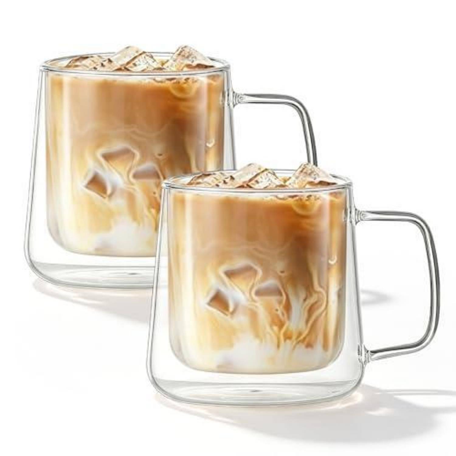 Zwei klare Glastassen mit Eiskaffee mit Milchschlieren und Eiswürfeln, auf weißem Hintergrund dargestellt.