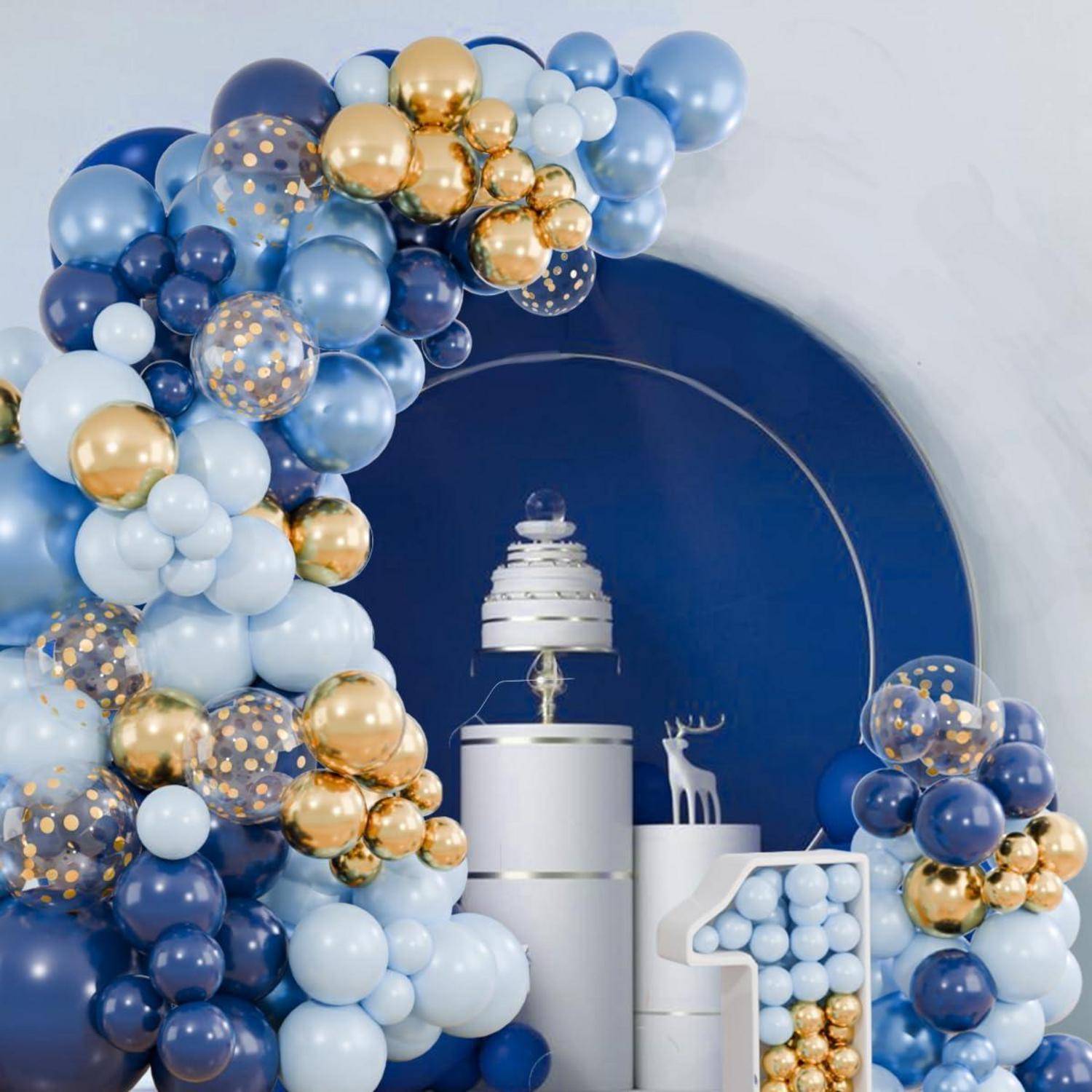 Dekorativer Ballonbogen in Blau, Weiß und Gold rahmt eine zentrale weiße mehrstöckige Kuchenpräsentation mit einer kleinen Hirschfigurine auf dunkelblauem Hintergrund ein.