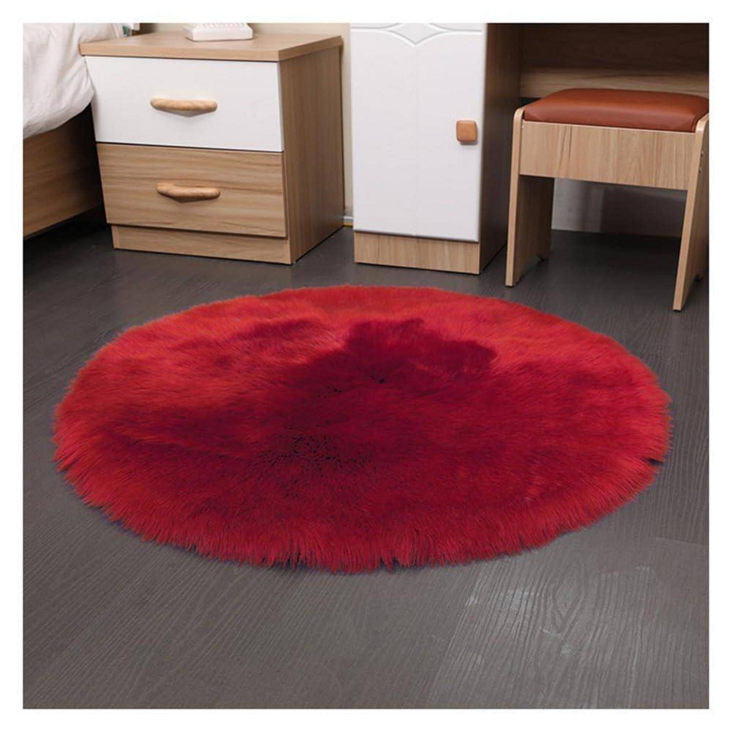 Runder roter Flokati-Teppich auf einem dunklen Holzboden in einem Schlafzimmer, neben einem Nachttisch und einem Stuhl.