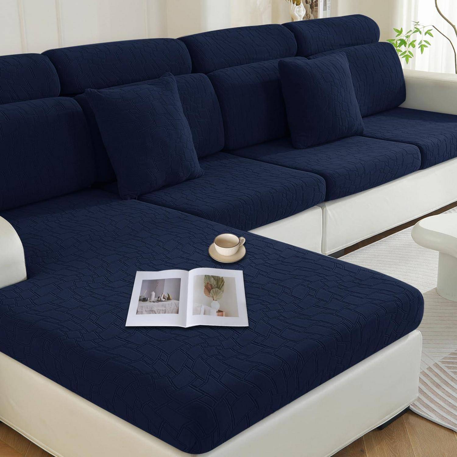 Dunkelblauem Ecksofa mit weißer Basis in einem hellen Wohnzimmer, mit einer offenen Zeitschrift und einer Kaffeetasse auf der Chaiselongue.