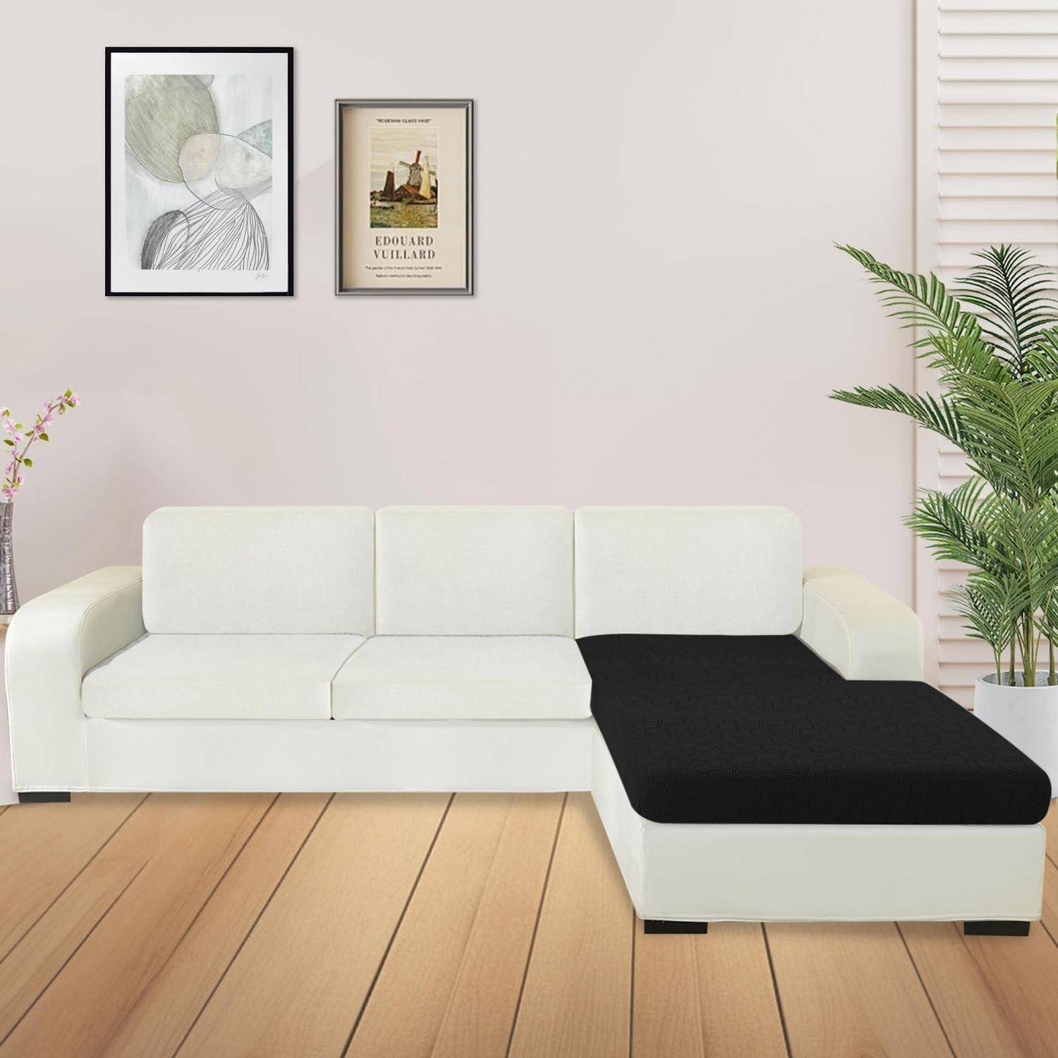 Modernes Wohnzimmer mit weißem Ecksofa und schwarzer Chaiselongue, gerahmte Wandkunst darüber, Holzboden und Topfpflanzen.