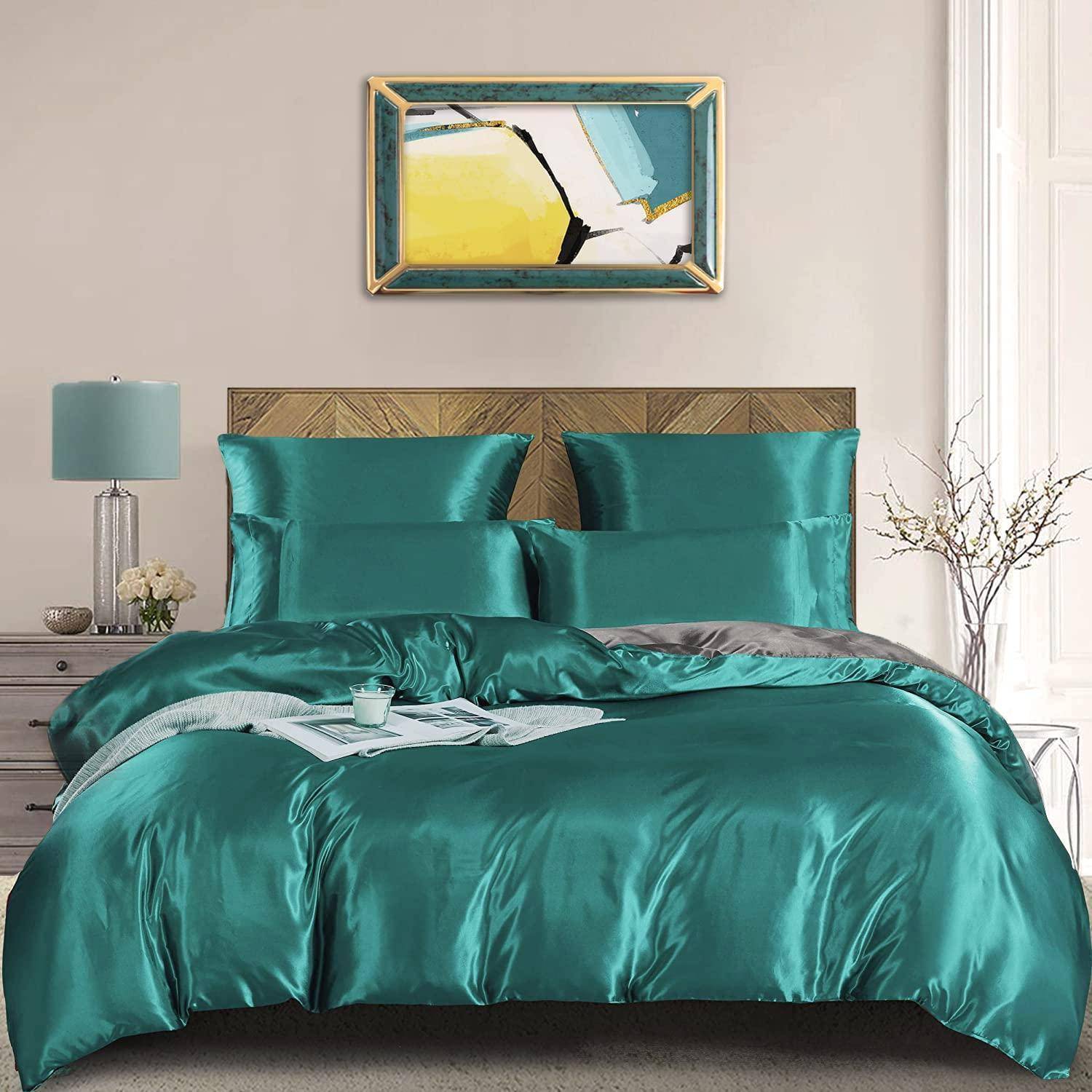Ein ordentlich gemachtes Bett mit blaugrüner Satinbettwäsche und Kissen, flankiert von einer Lampe und Dekoration auf Nachttischen, in einem hellen Schlafzimmer.
