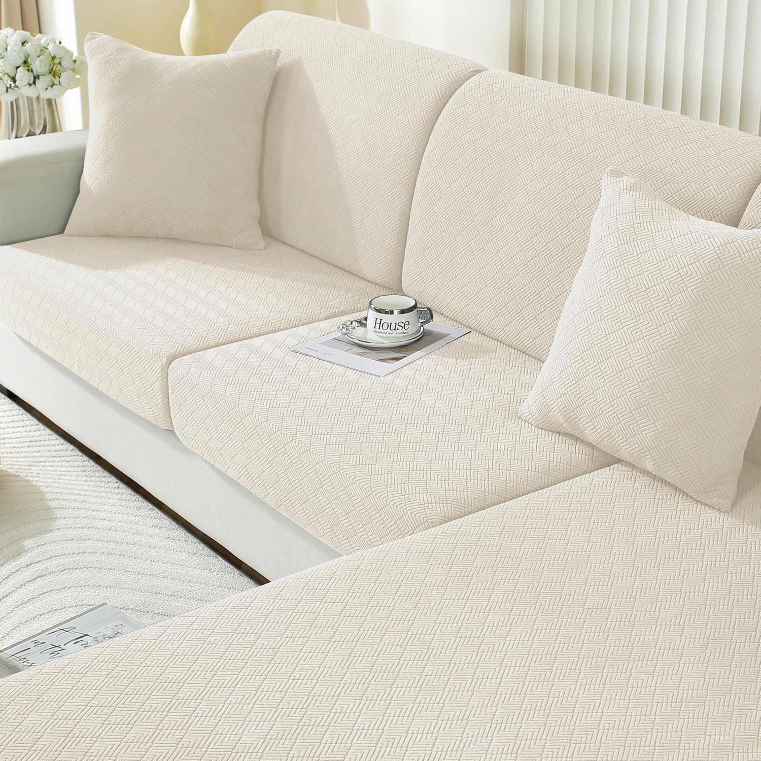 Cremefarbenes Ecksofa mit strukturiertem Stoff und Kissen, stilisiert mit einer Kaffeetasse und Magazin in einem hellen Wohnzimmer.