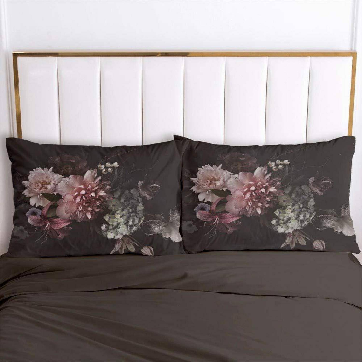 Ein sorgfältig gemachtes Bett mit weiß gepolstertem Kopfteil, dunkelgrauem Bettzug und zwei Kissen mit Blumenmuster.