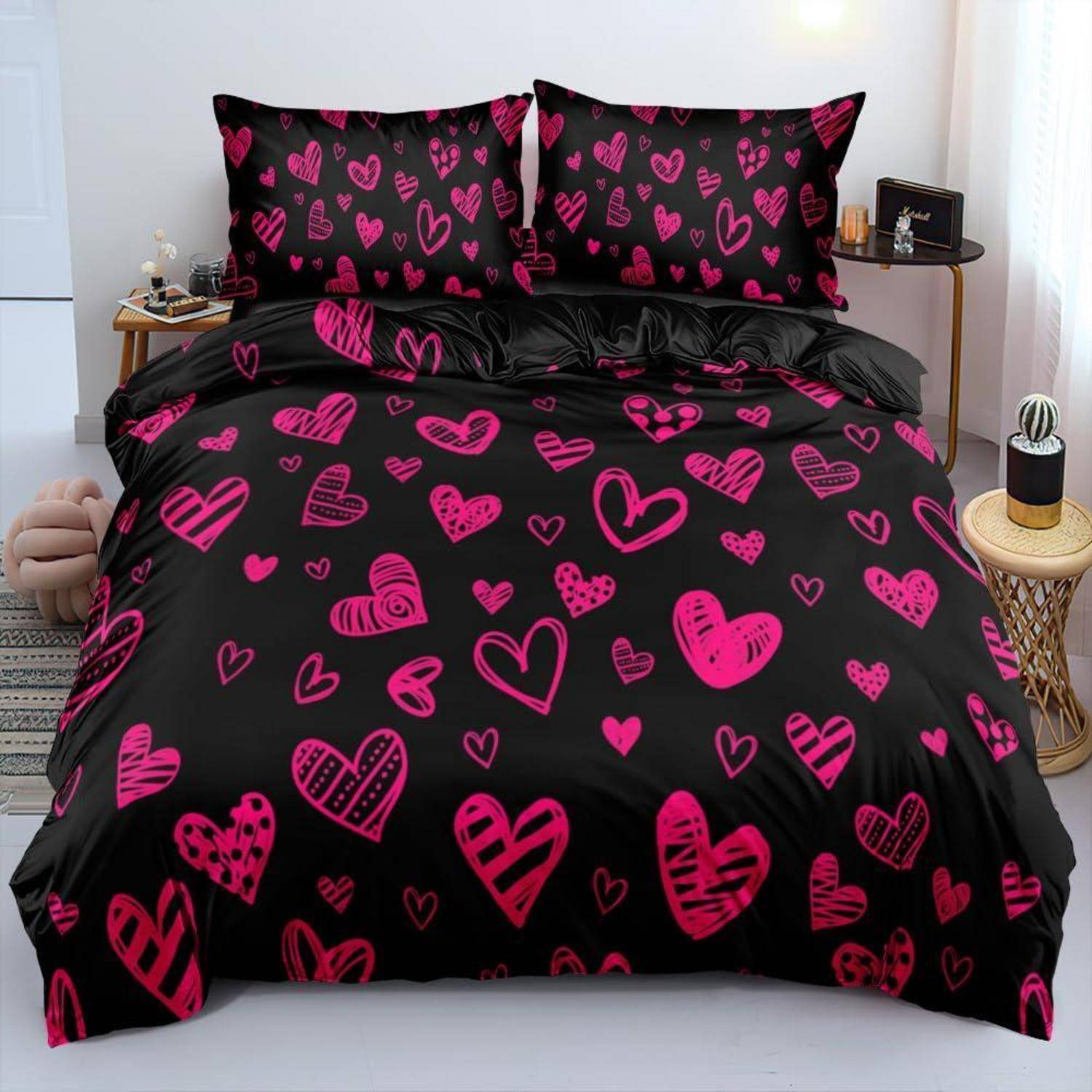 Schwarzes Bettwäscheset mit leuchtend rosa Herzmustern, bestehend aus einer Bettdecke und zwei passenden Kissenbezügen auf einem ordentlich gemachten Bett.