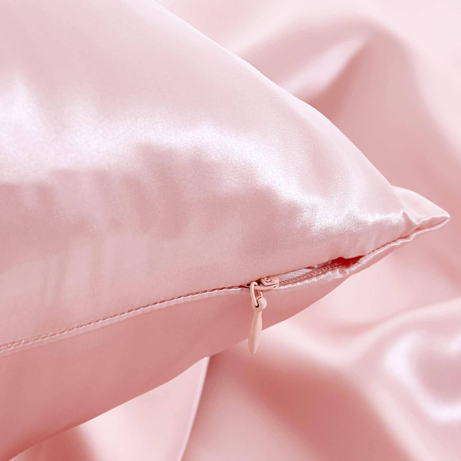 Nahaufnahme eines hellrosa Satinkissens mit sichtbarem Reißverschluss, vor einem passenden rosa Stoff.