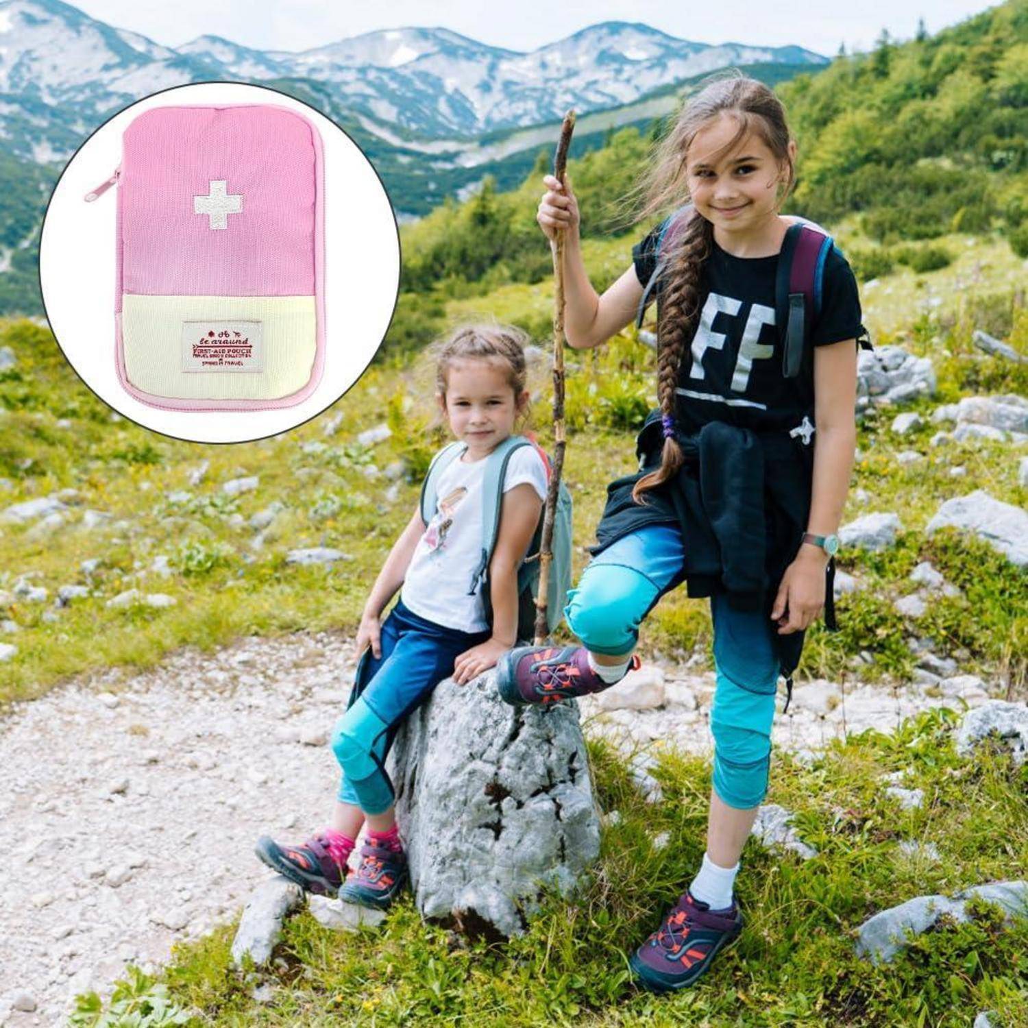 Zwei Mädchen auf einem Bergpfad, eines hält einen Wanderstock neben einem Felsen; Einsatz zeigt eine rosa-weiße Erste-Hilfe-Tasche.