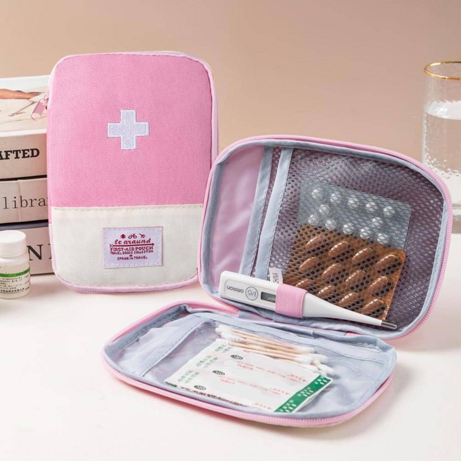 Rosa Erste-Hilfe-Tasche und Organizer offen, um Netztaschen mit medizinischen Vorräten und ein Thermometer zu zeigen, mit einem Kreuzzeichen auf der Vorderseite.