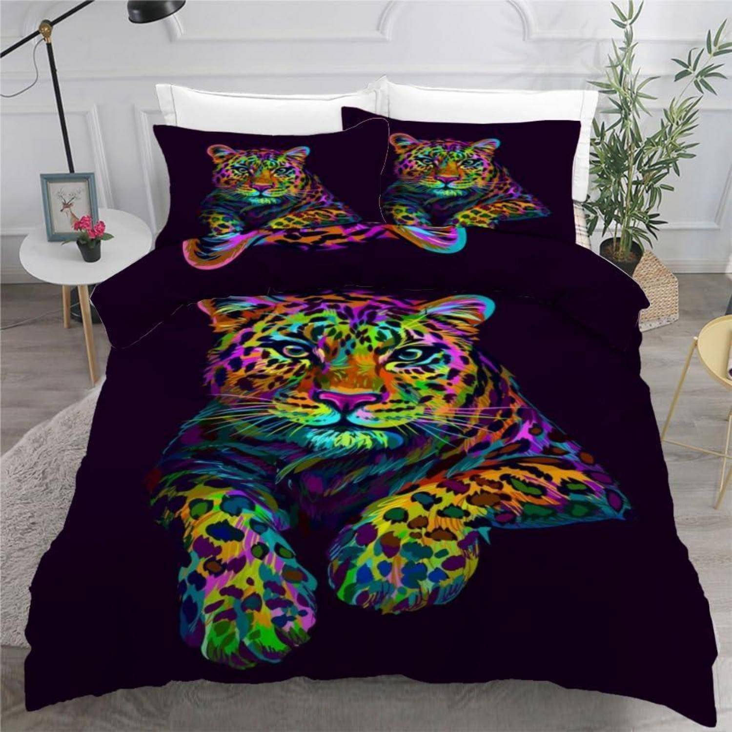 Ein Bett mit schwarzer Bettwäsche, das auf der Bettdecke und den Kissen leuchtend bunte Leopardenmuster mit Regenbogenfarben aufweist, in einem modernen Schlafzimmer.
