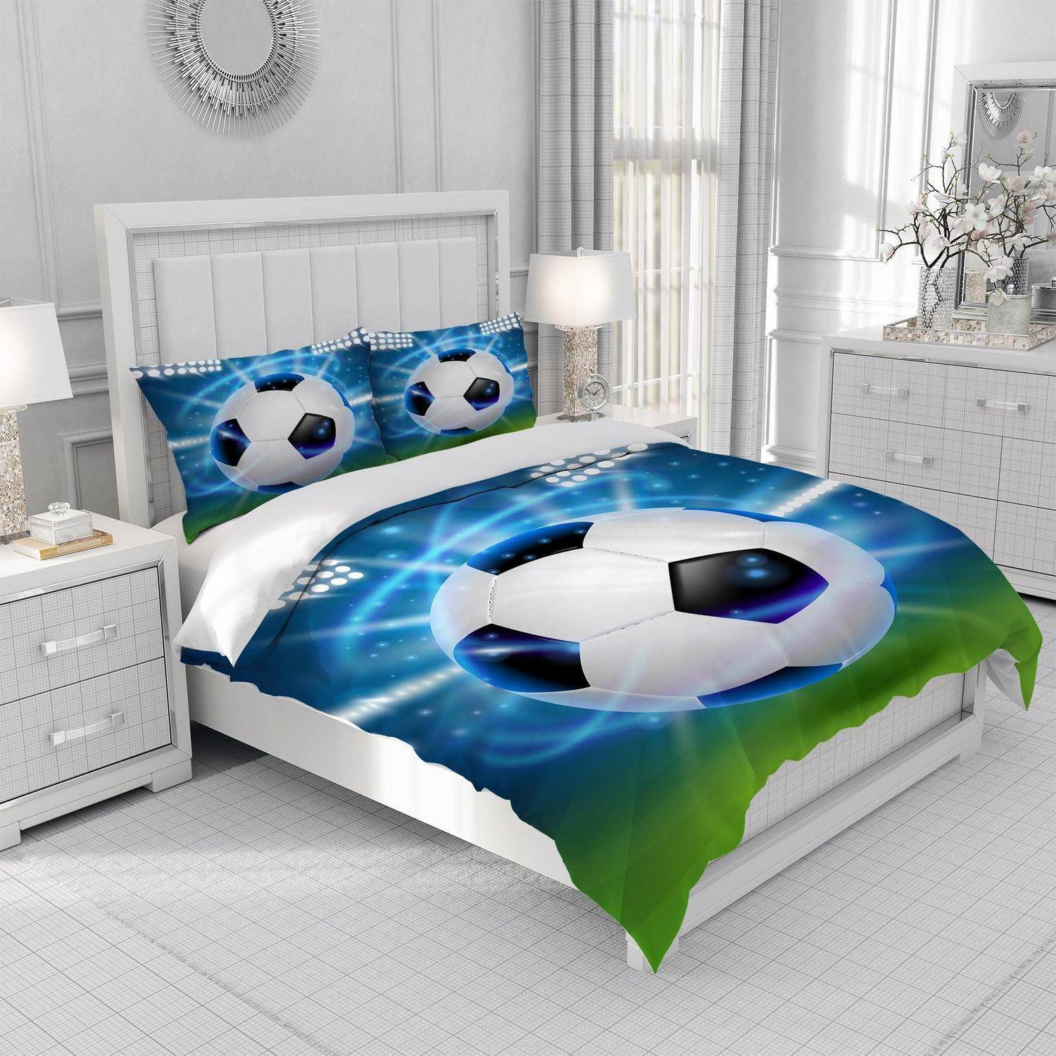Ein Bett mit Fußball-Thema-Bettwäsche und passenden Kissen in einem hell weißen Schlafzimmer mit Nachttischen, Lampen und einer Kommode.