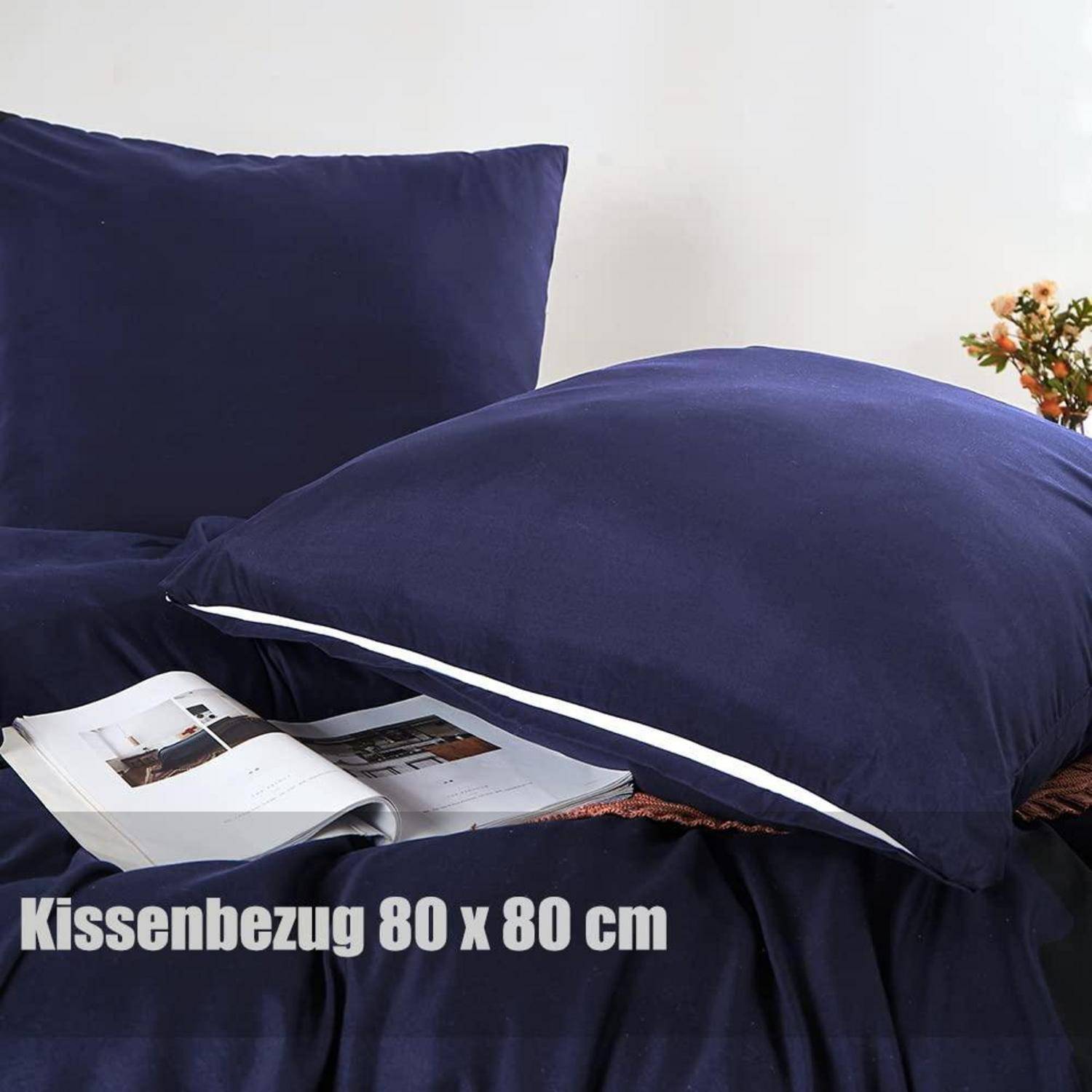 Marineblaues quadratisches Kissenbezug auf einem Bett, gezeigt mit einem offenen Magazin; übergelagerter Text lautet „Kissenbezug 80 x 80 cm".