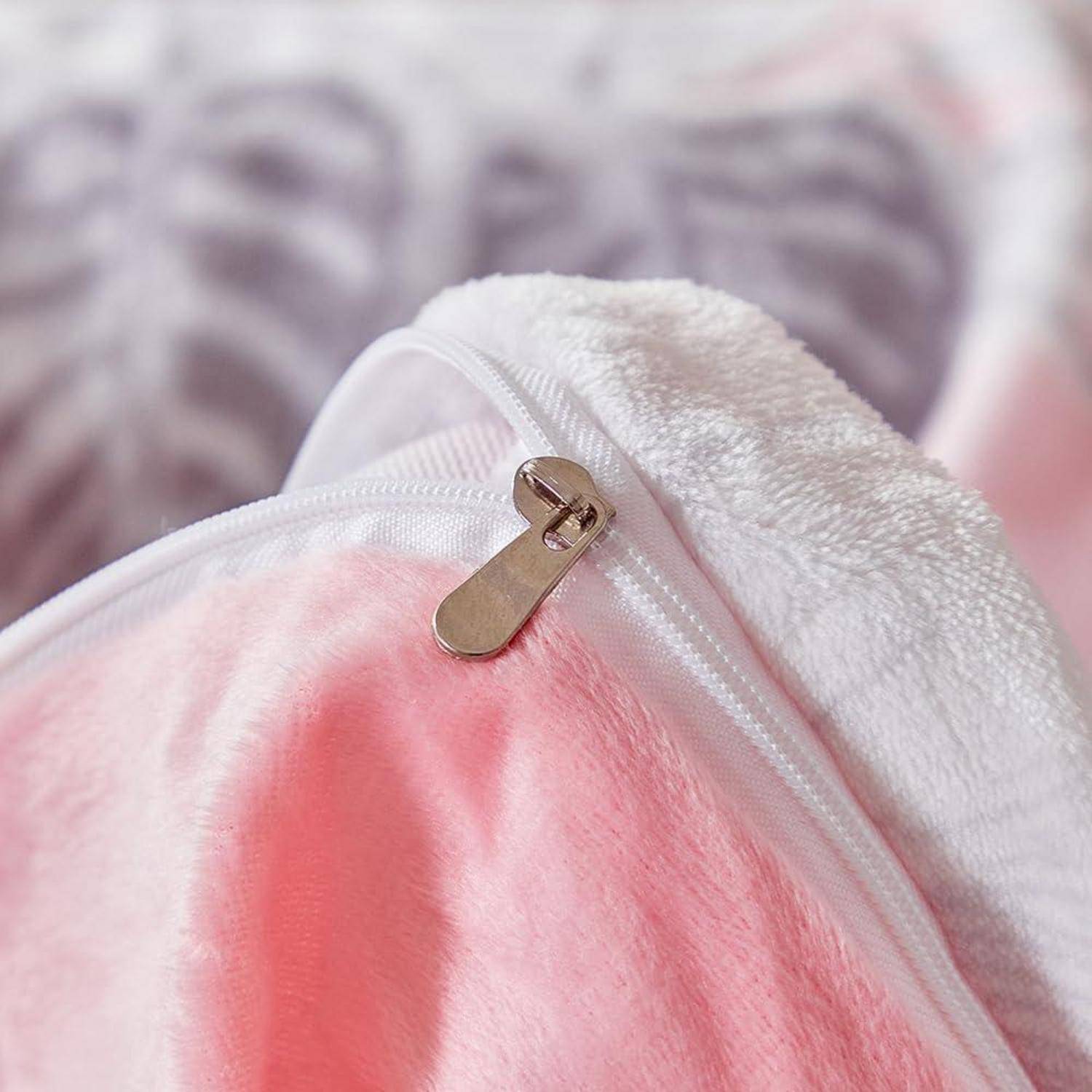 Nahaufnahme einer rosa-weißen Plüschdecke oder einem Handtuch mit einem Reißverschluss, gefaltet auf einer weich gemusterten Oberfläche.