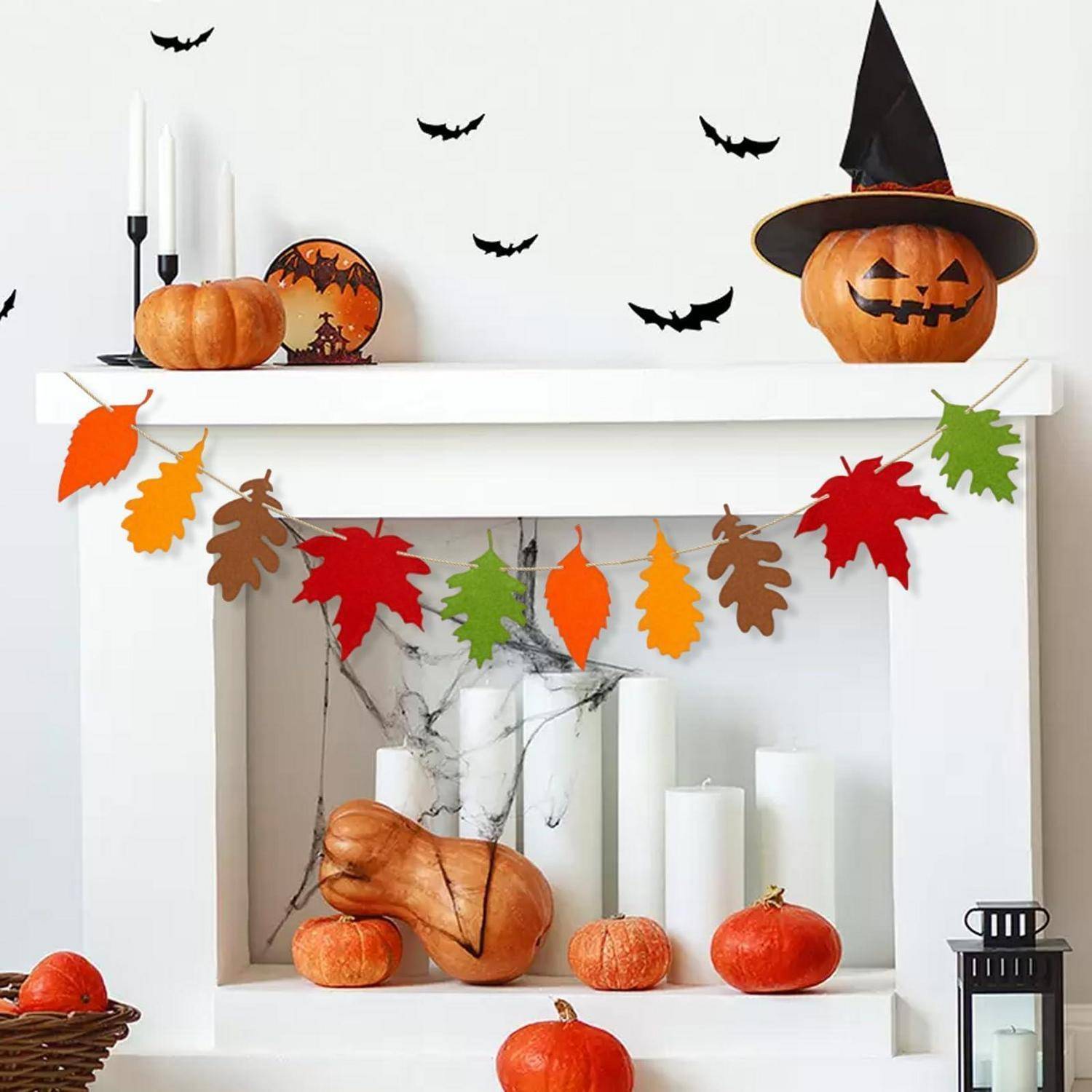 Halloweendeko auf dem Kaminsims mit Kürbissen, Fledermausausschnitten, Herbstlaubgirlande, Kerzen und einer geschnitzten Kürbislaterne mit Hexenhut.