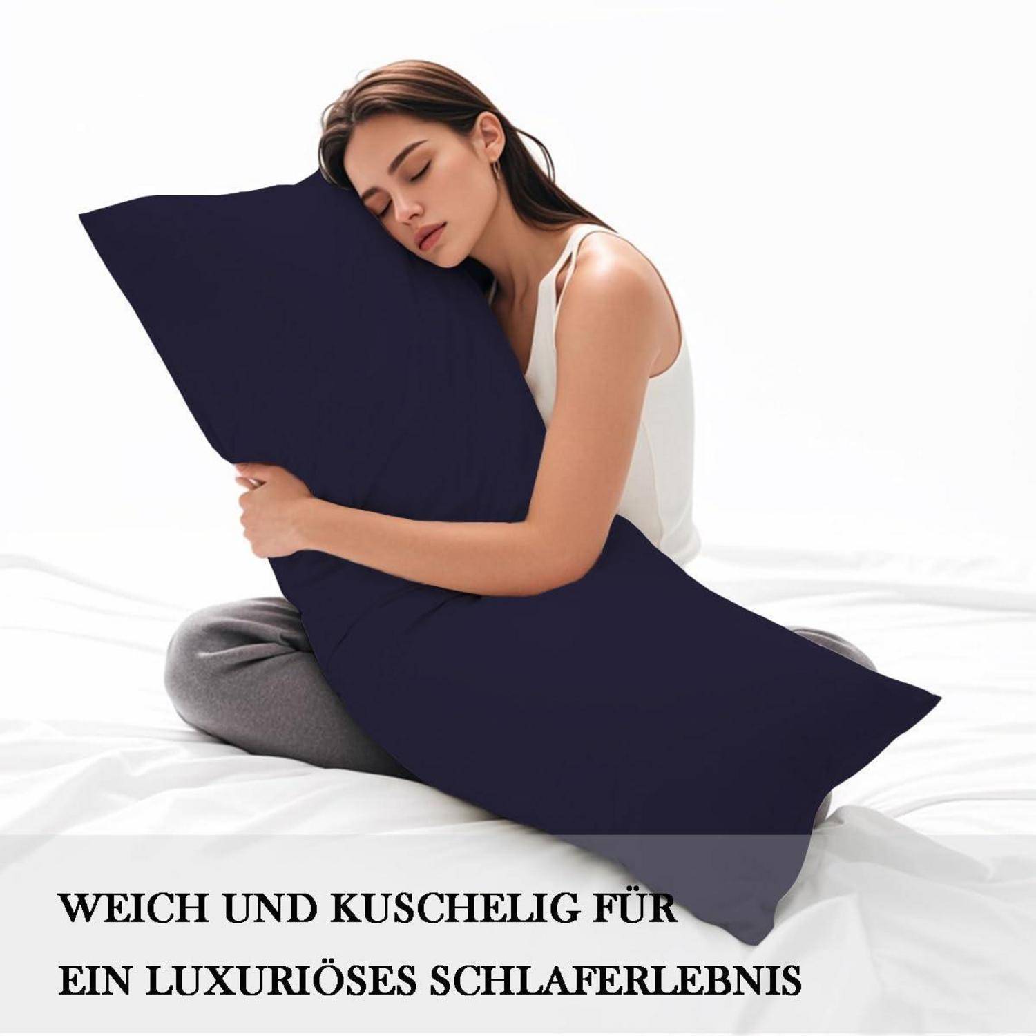Frau, die ein dunkelmarineblau Körperkissen auf einem Bett umarmt, mit deutschem Text: 'WEICH UND KUSCHELIG FÜR EIN LUXURIÖSES SCHLAFERLEBNIS'.