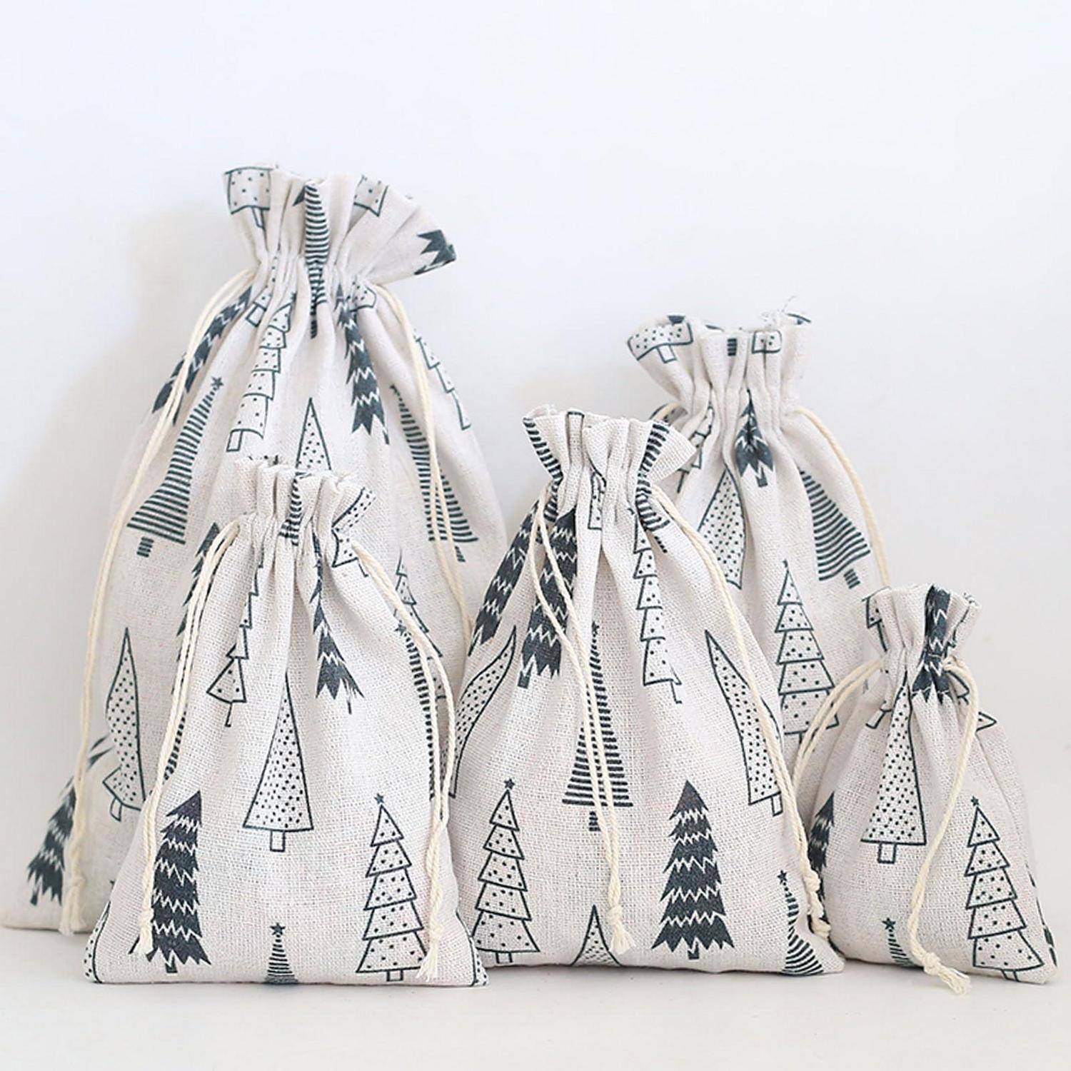 Vier gebundene Stoffgeschenktaschen in verschiedenen Größen mit schwarzen Weihnachtsbaummustern auf weißem Hintergrund.