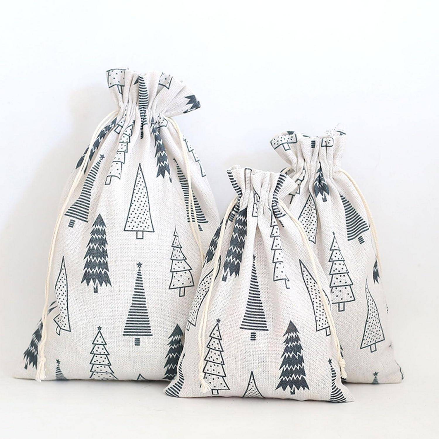 Drei Stoffgeschenktaschen mit Kordelzug und schwarzen Baummustern, gruppiert auf weißem Hintergrund.